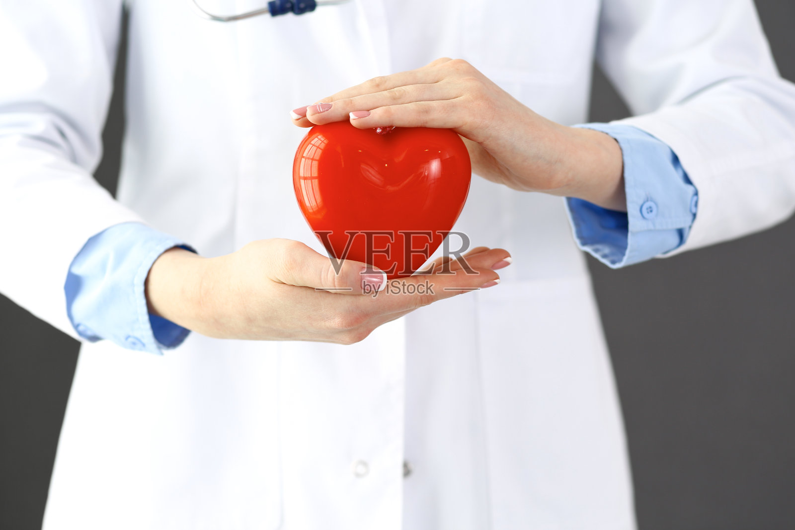 女医生用听诊器抱着心脏。医学中的保健和心脏病学概念照片摄影图片