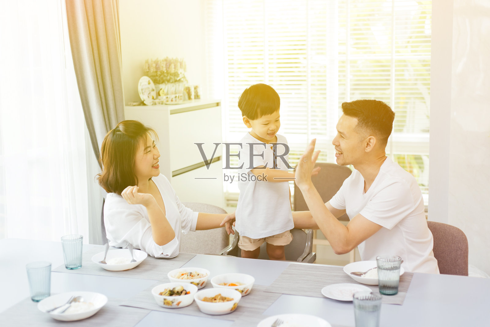 幸福的亚洲家庭在家里吃饭的时候互相击掌照片摄影图片