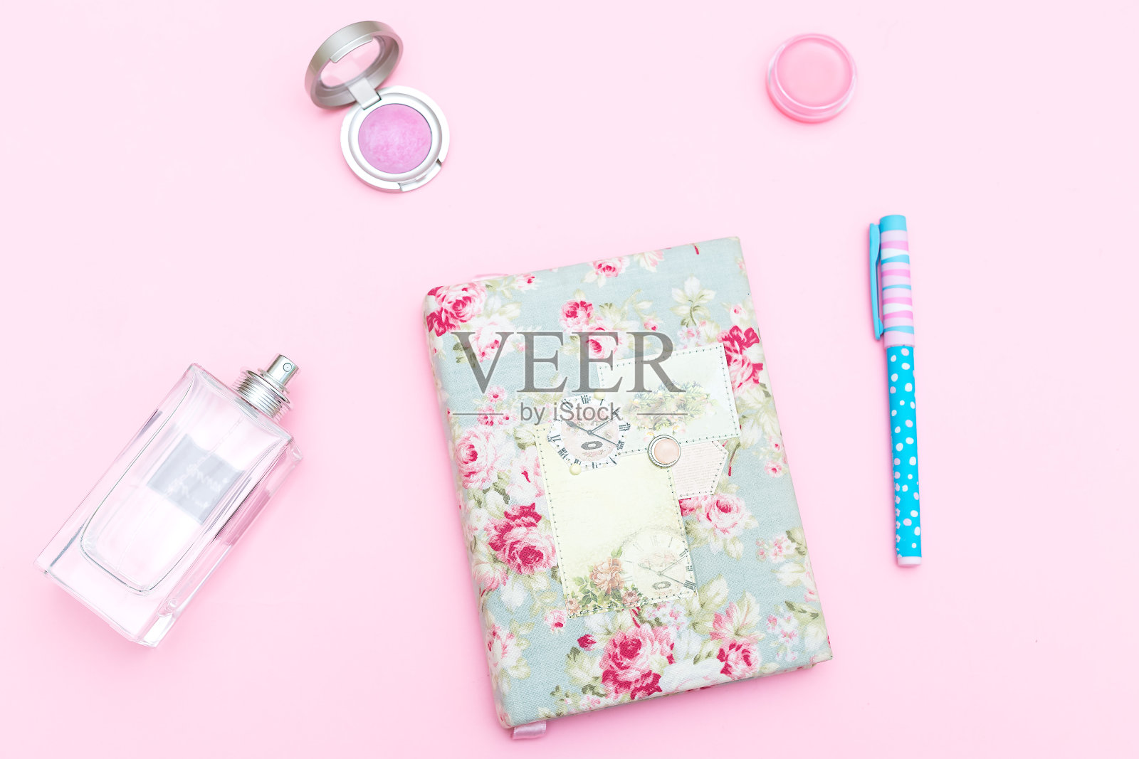 粉红色背景上的笔记本和女性配件。女性的桌子照片摄影图片