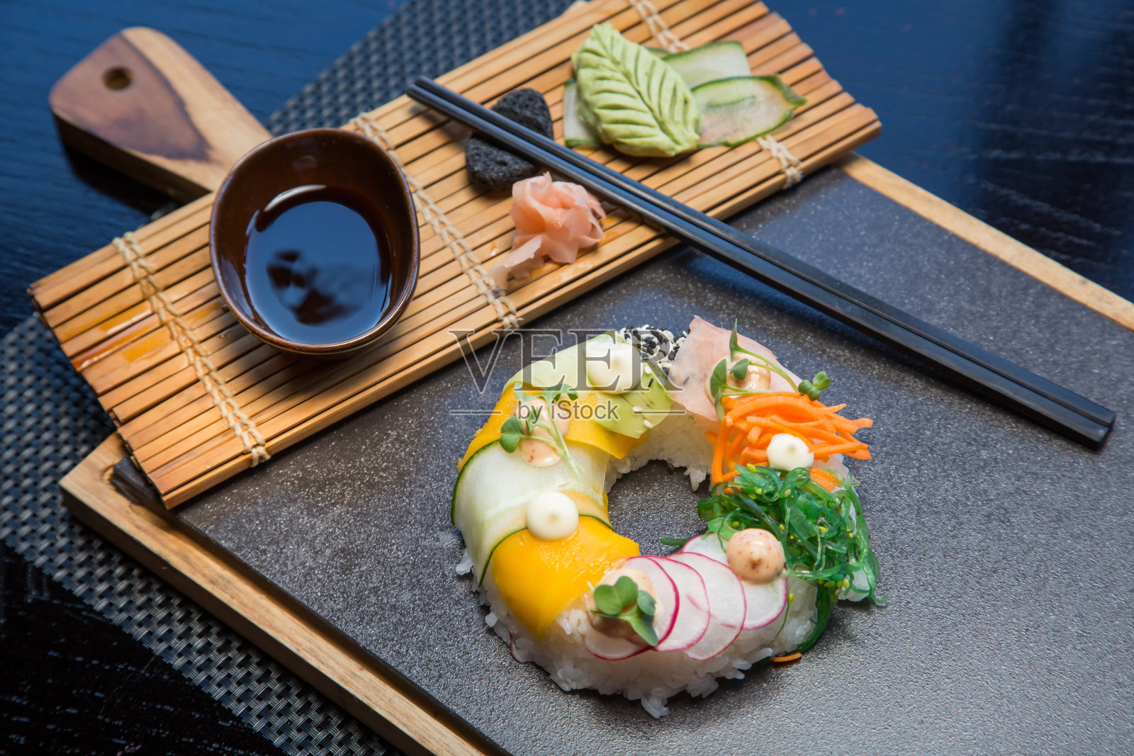 素菜寿司甜甜圈，配上姜、鳄梨、黄瓜、韭菜，放在石板上。Sushi-food混合动力车的趋势。高端美食照片摄影图片