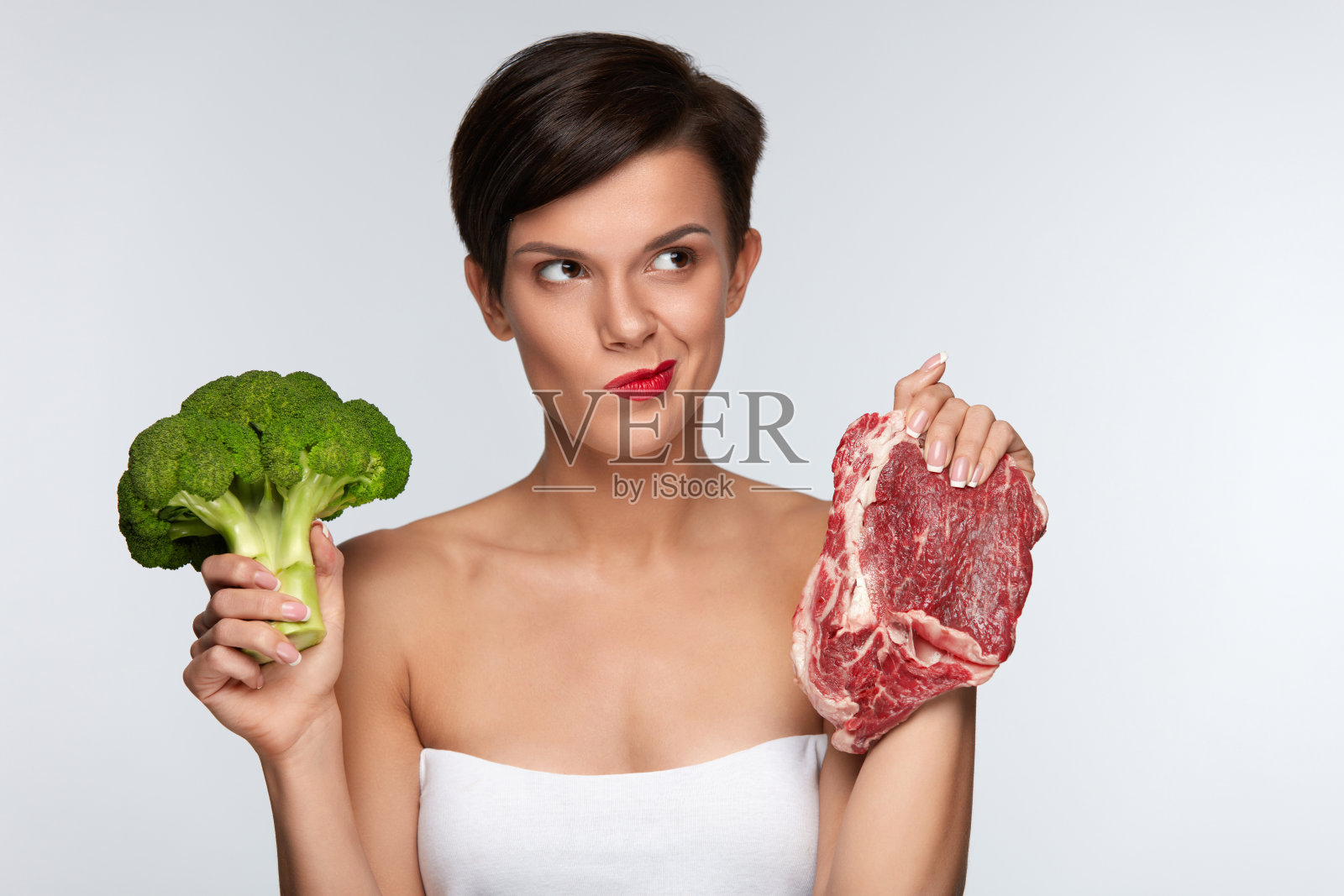 美女在肉和西兰花之间的选择。健康的饮食习惯照片摄影图片