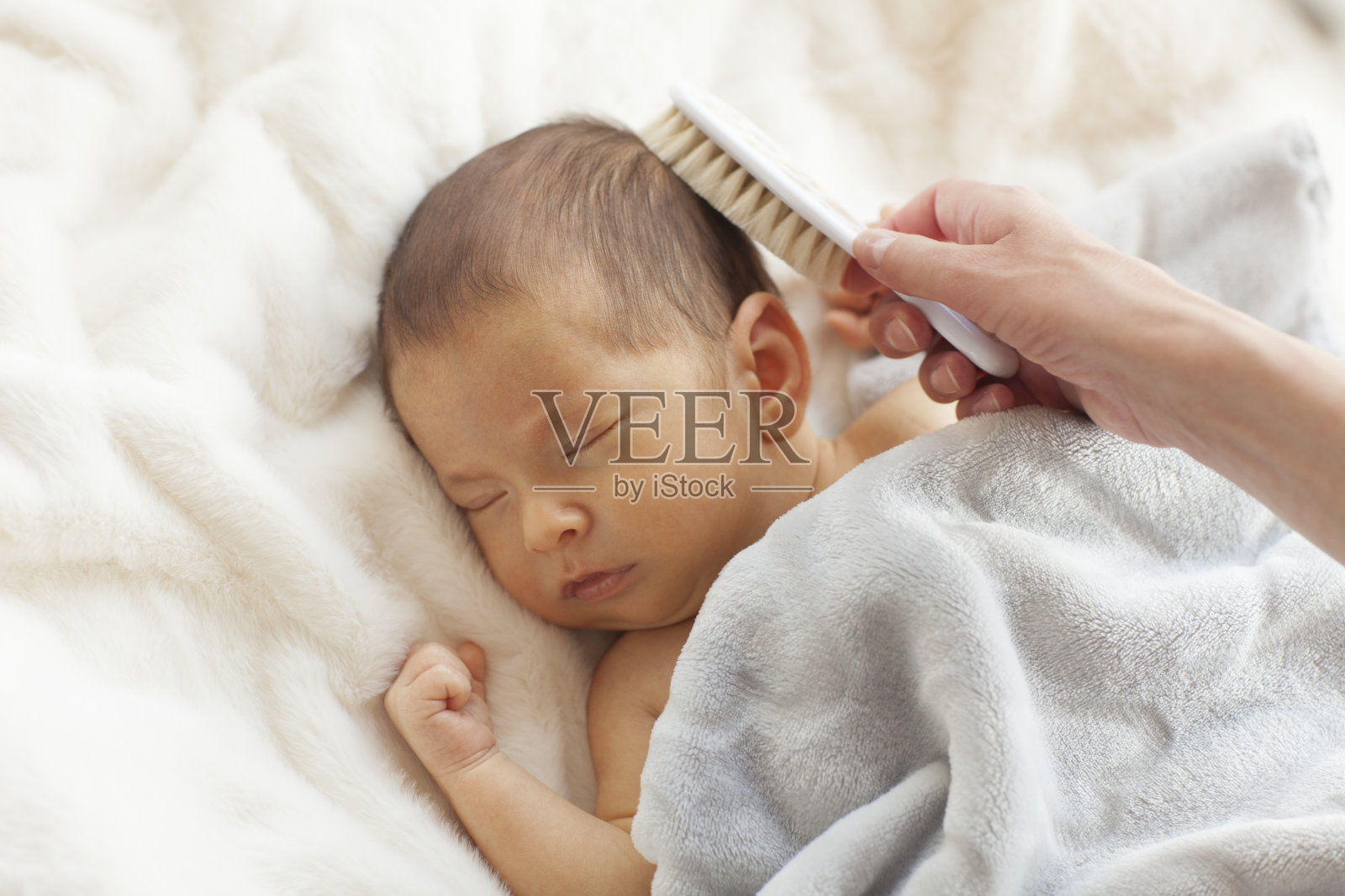 一位年轻的母亲正在梳理新生儿的头发照片摄影图片