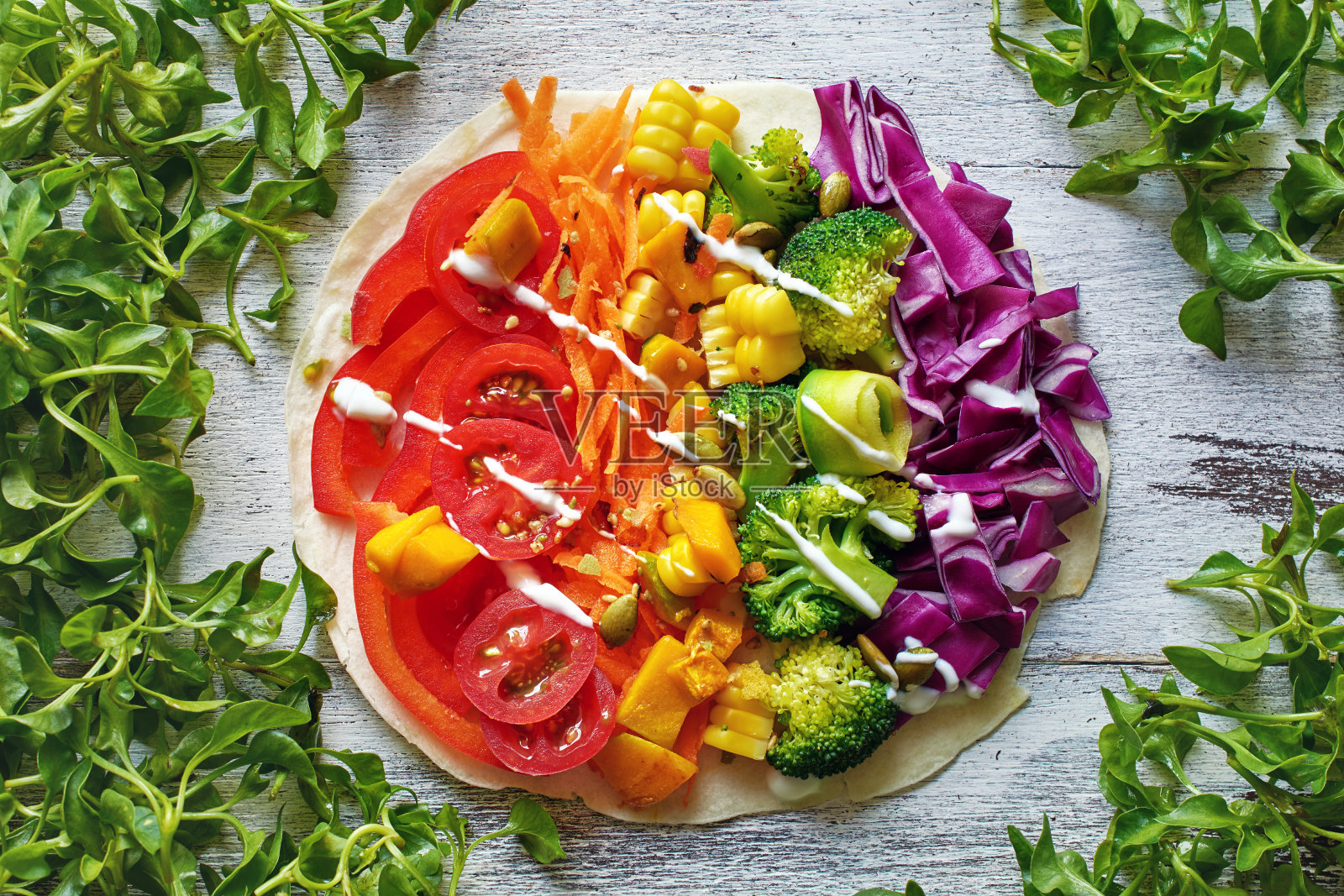 俯视图素食披萨与彩虹色的蔬菜，种子，酸奶酱和皮塔面包在白色的桌子上。照片摄影图片