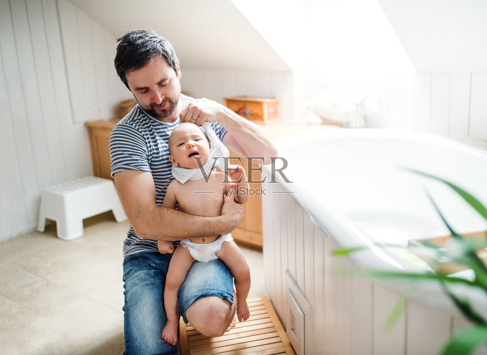 父亲带着一个蹒跚学步的孩子在家，准备洗澡。照片摄影图片