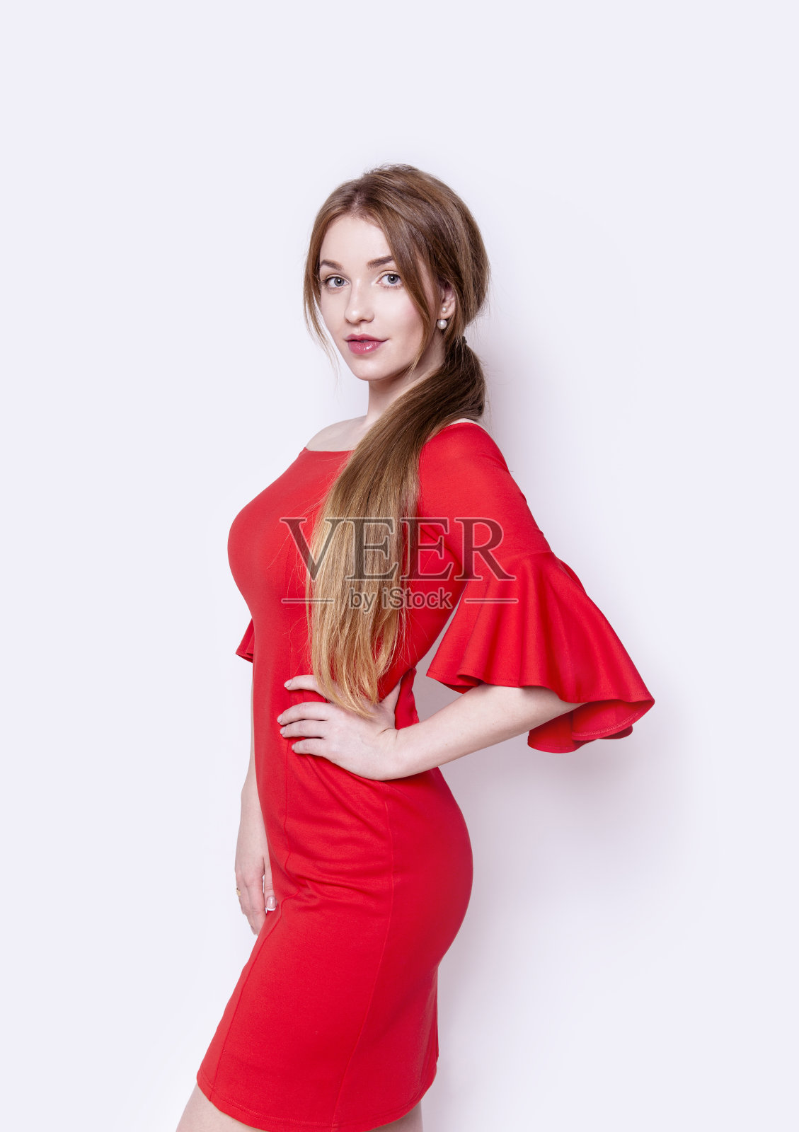 漂亮的年轻女子穿着时尚优雅的红色连衣裙，手放在臀部的工作室肖像照片摄影图片