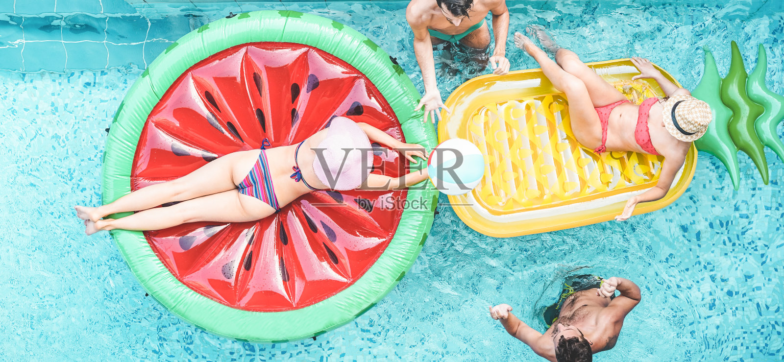 快乐的朋友在游泳池里玩气垫球-年轻人在暑假里玩-旅游，假期，青年生活方式，友谊和热带概念照片摄影图片