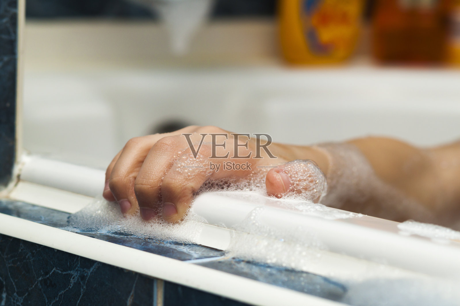 孩子在沐浴时用洗发水泡沫洗手。保健和卫生理念。照片摄影图片