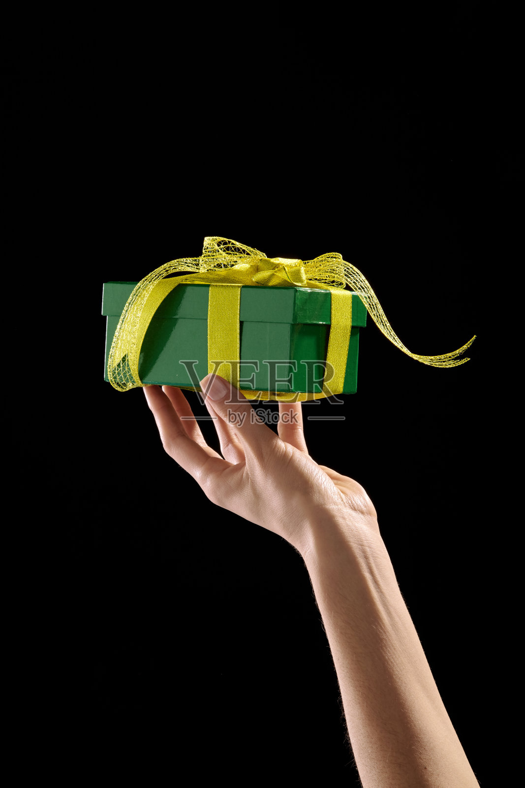 手握绿色礼盒与黄色丝带照片摄影图片