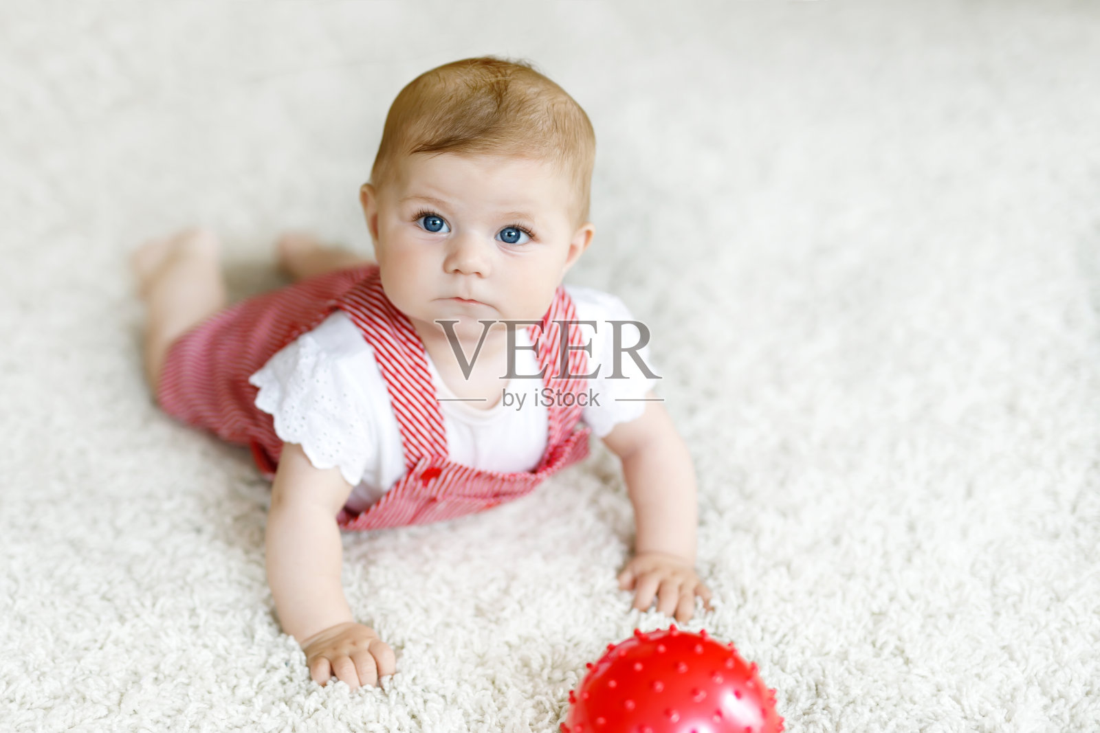 可爱的小女孩在玩红色的口香糖球。照片摄影图片