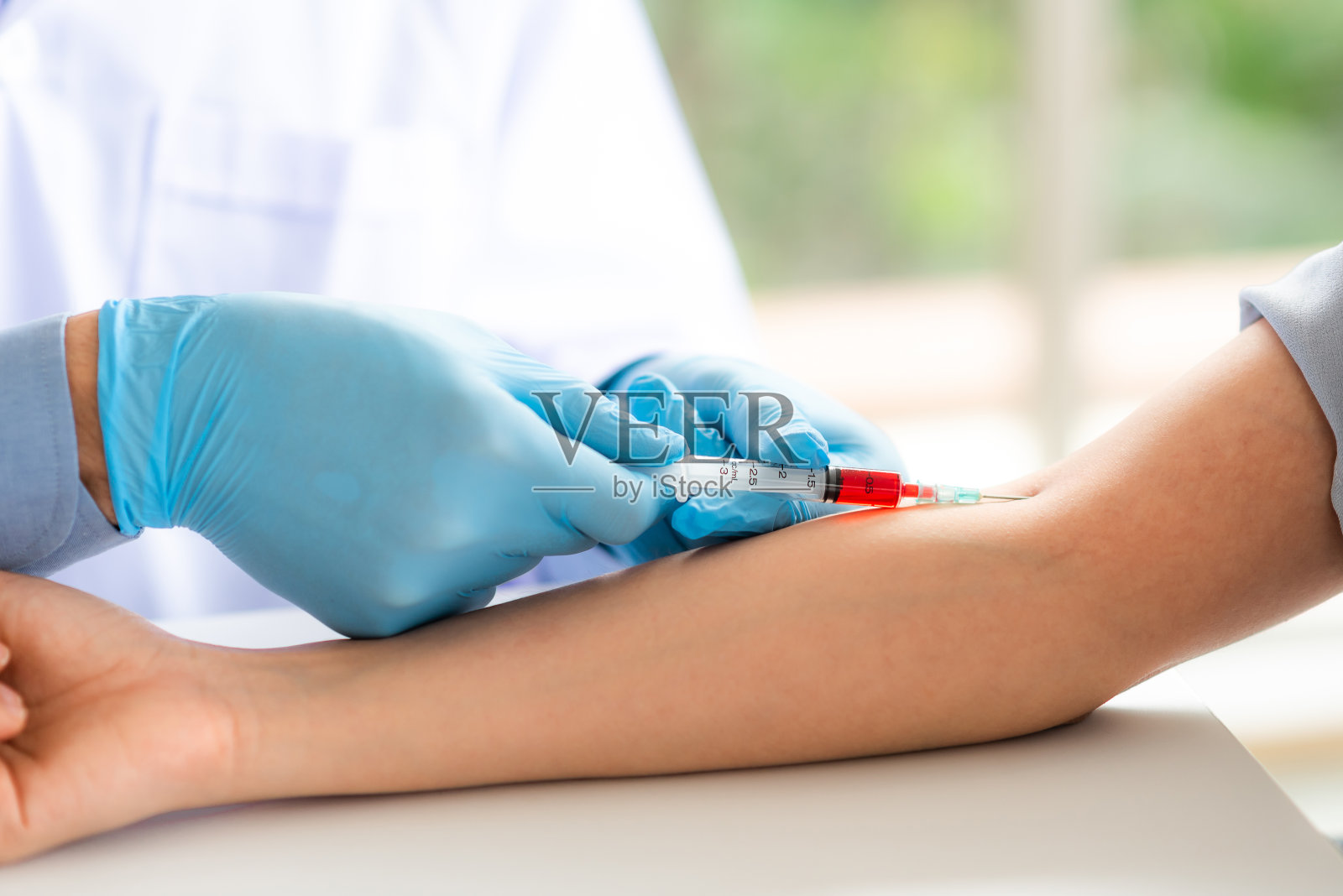 医生用注射器从病人手臂上取血照片摄影图片