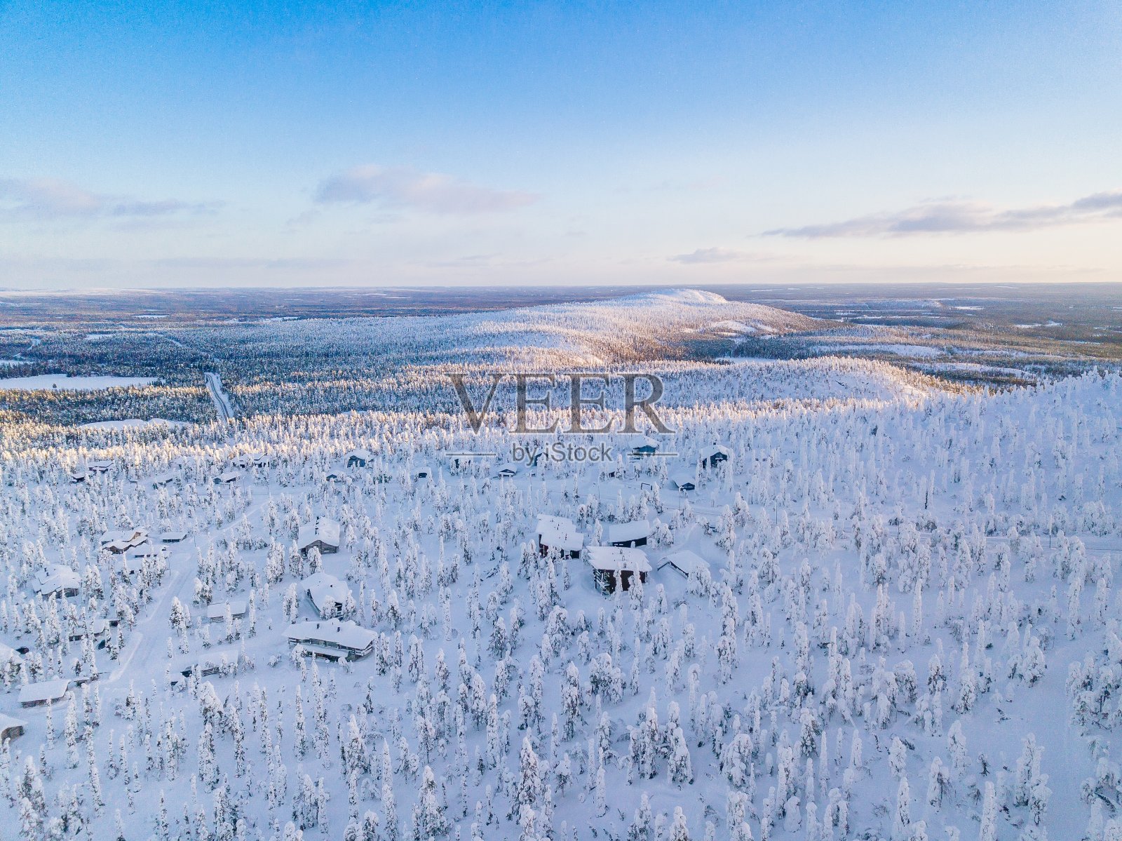 鸟瞰图的冬季森林与结霜的树木，农村道路和村庄在芬兰照片摄影图片