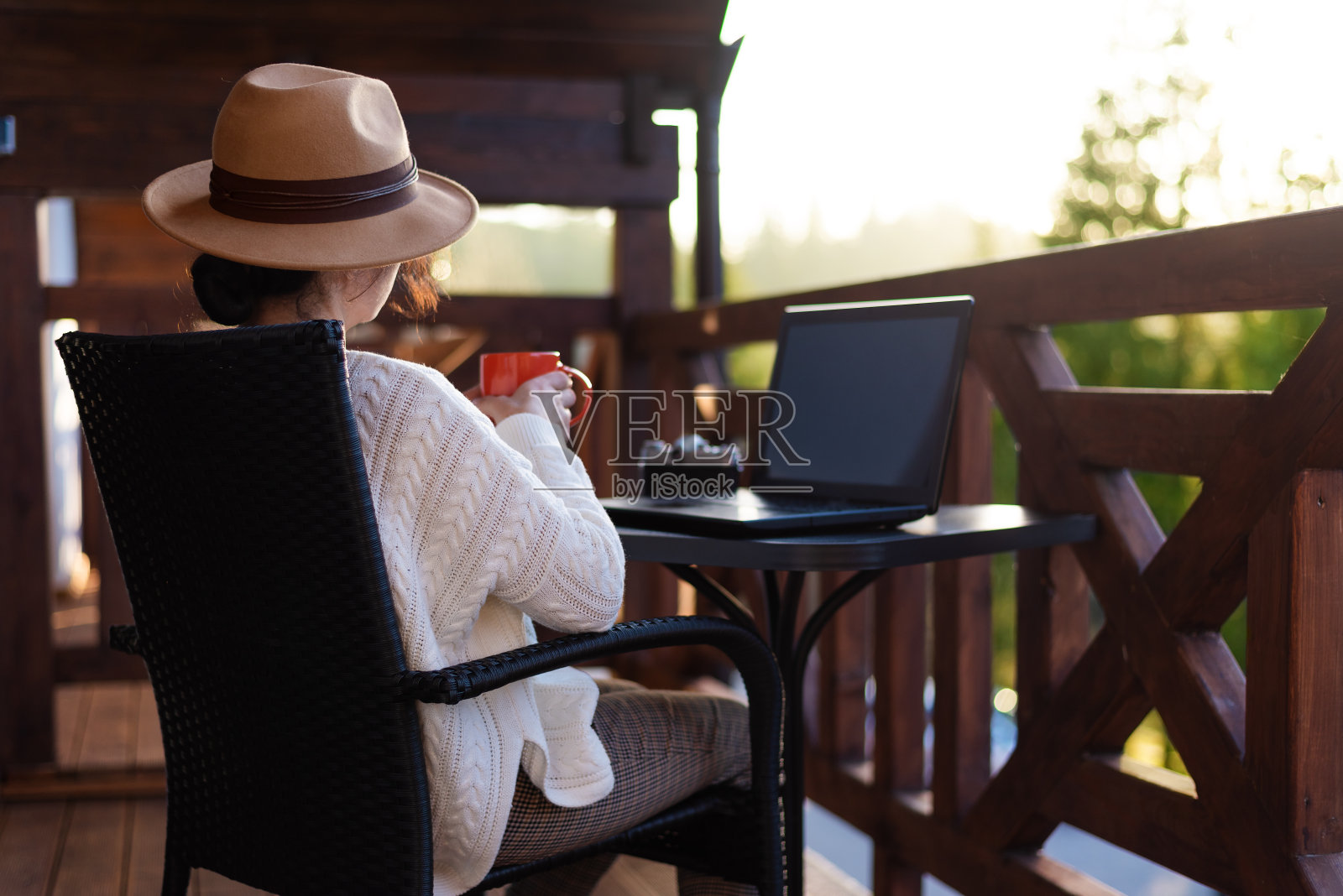 年轻的女游客坐在露台上，拿着笔记本电脑，喝着茶。照片摄影图片