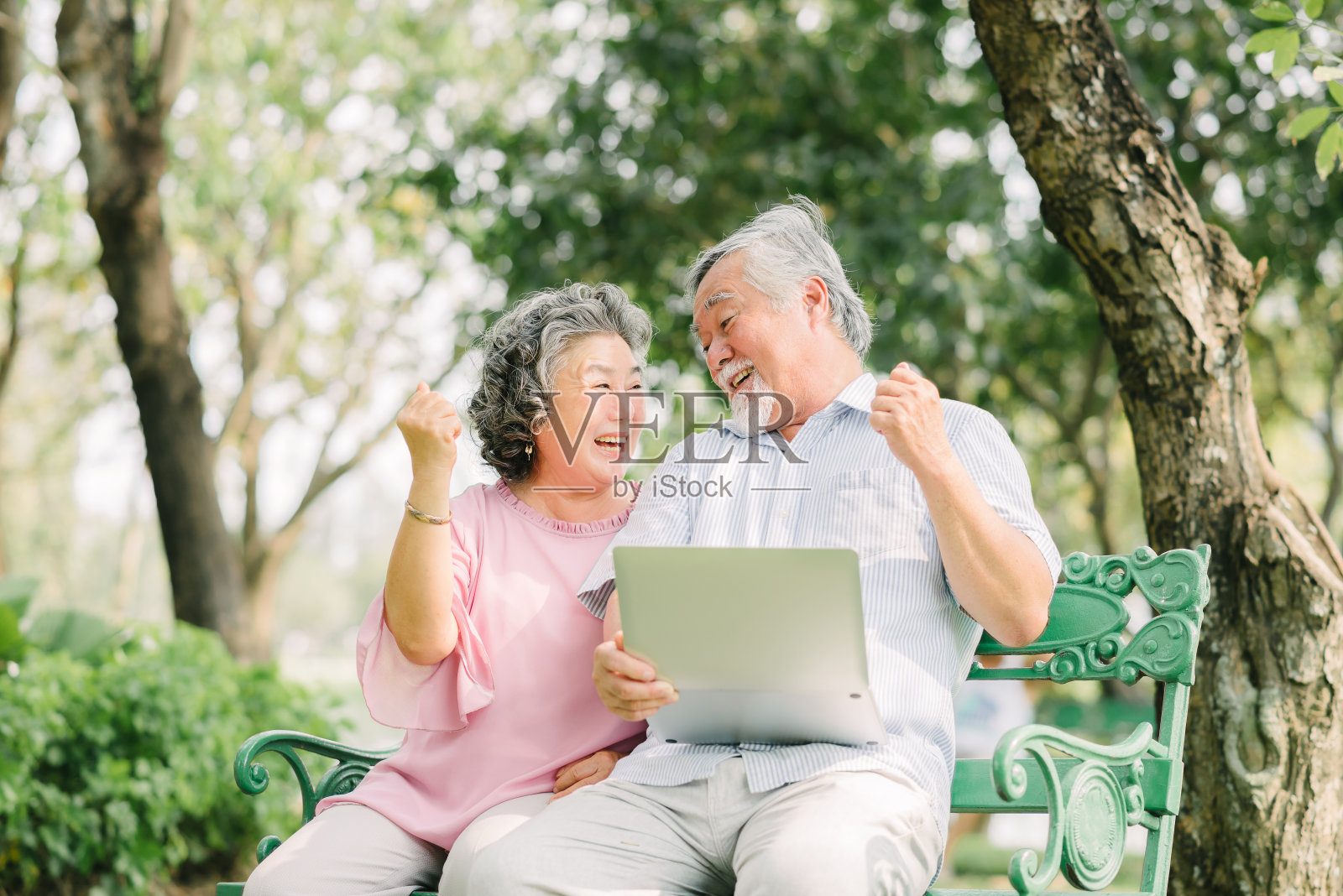 快乐的亚洲老夫妇在公园里拿着笔记本电脑照片摄影图片