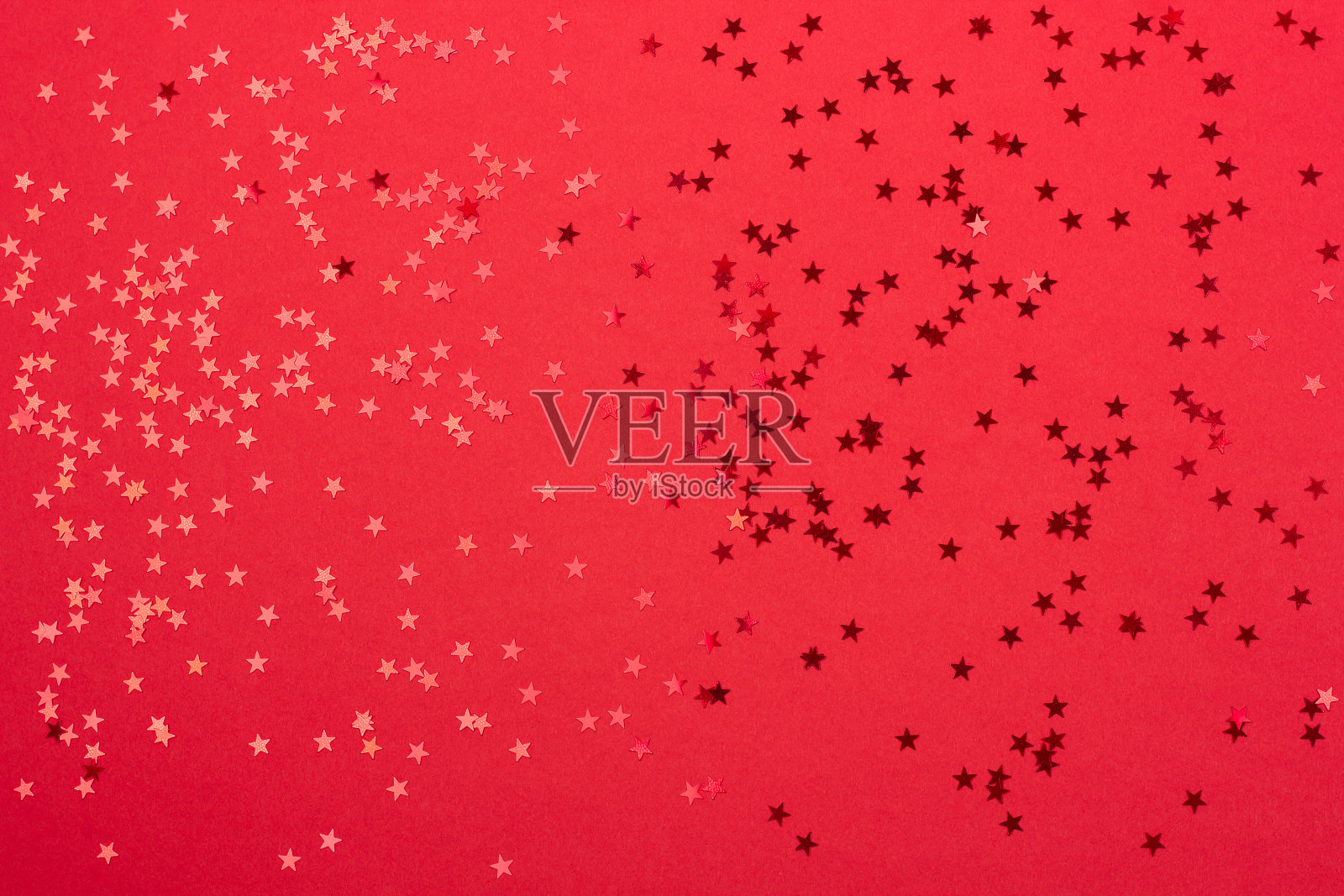 金属星形五彩纸屑在喜庆的红色背景上。照片摄影图片