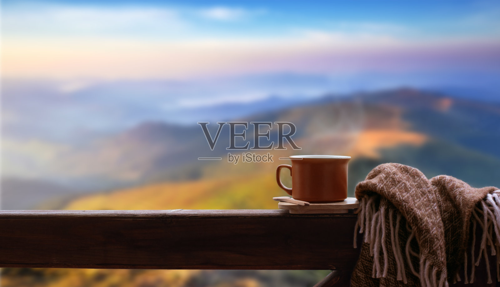 一杯热茶或咖啡，在山上的木栏杆上。照片摄影图片