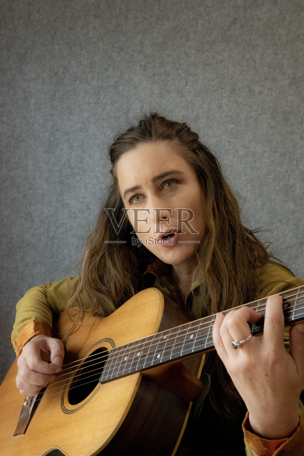 年轻女子弹吉他唱歌。照片摄影图片