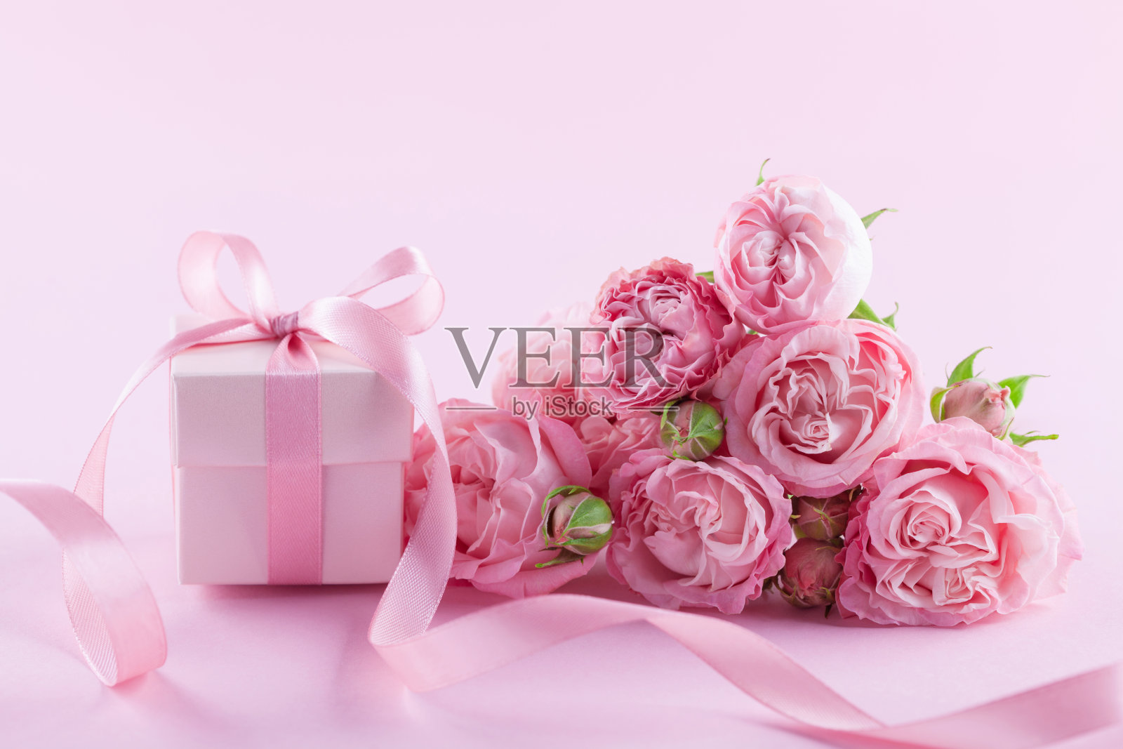 礼物或礼物盒和美丽的玫瑰花在粉红色的背景。妇女节或母亲节的贺卡。照片摄影图片