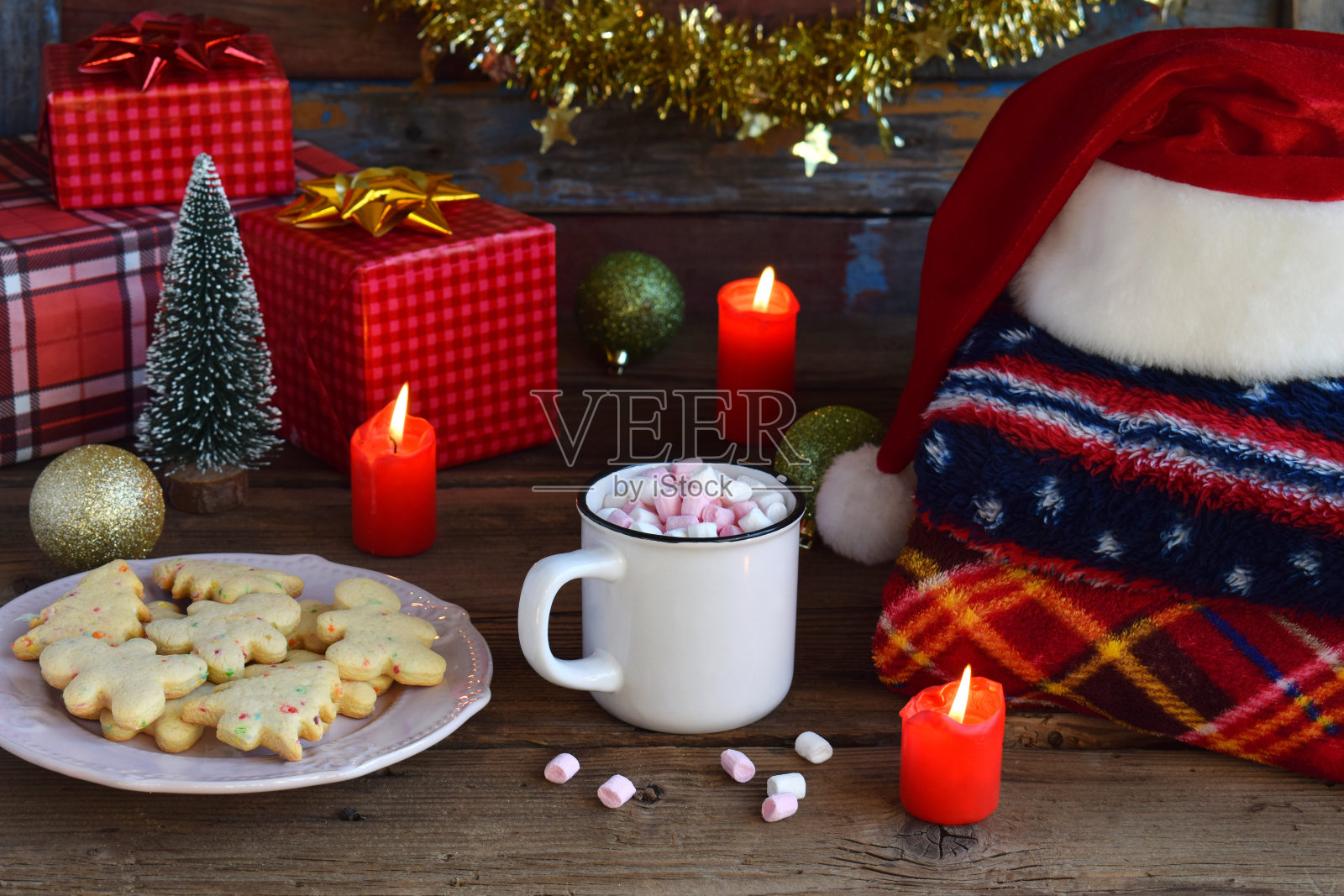 圣诞和新年作文。格子图案，圣诞老人帽，可可杯，棉花糖，姜饼饼干，木制背景上的圣诞树装饰。寒假的概念照片摄影图片