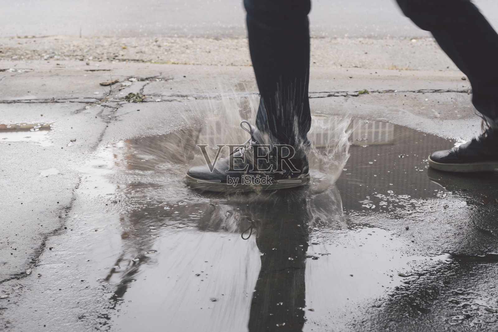 男脚踩进水坑，溅起了大水花照片摄影图片