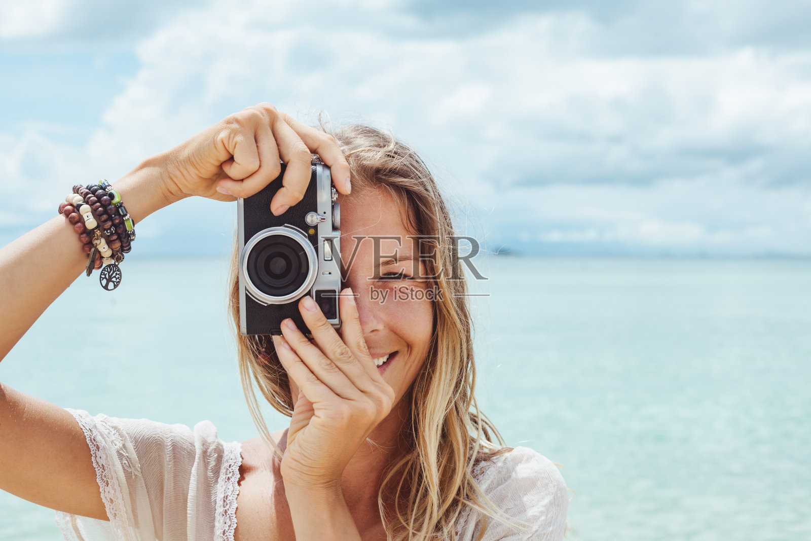 用复古相机在海上拍照的女孩照片摄影图片
