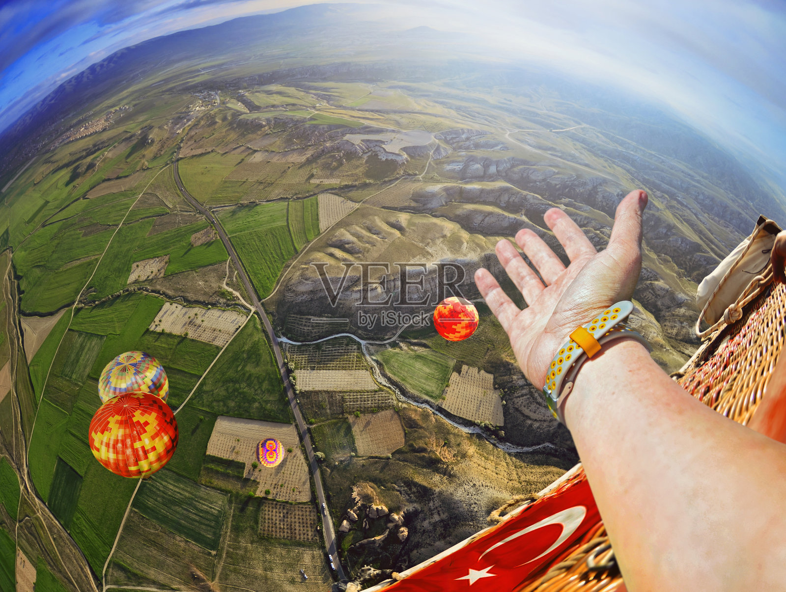 一个人的手在天空的特写视图。彩色的热气球在土耳其卡帕多西亚的蓝天上飞过岩石景观照片摄影图片