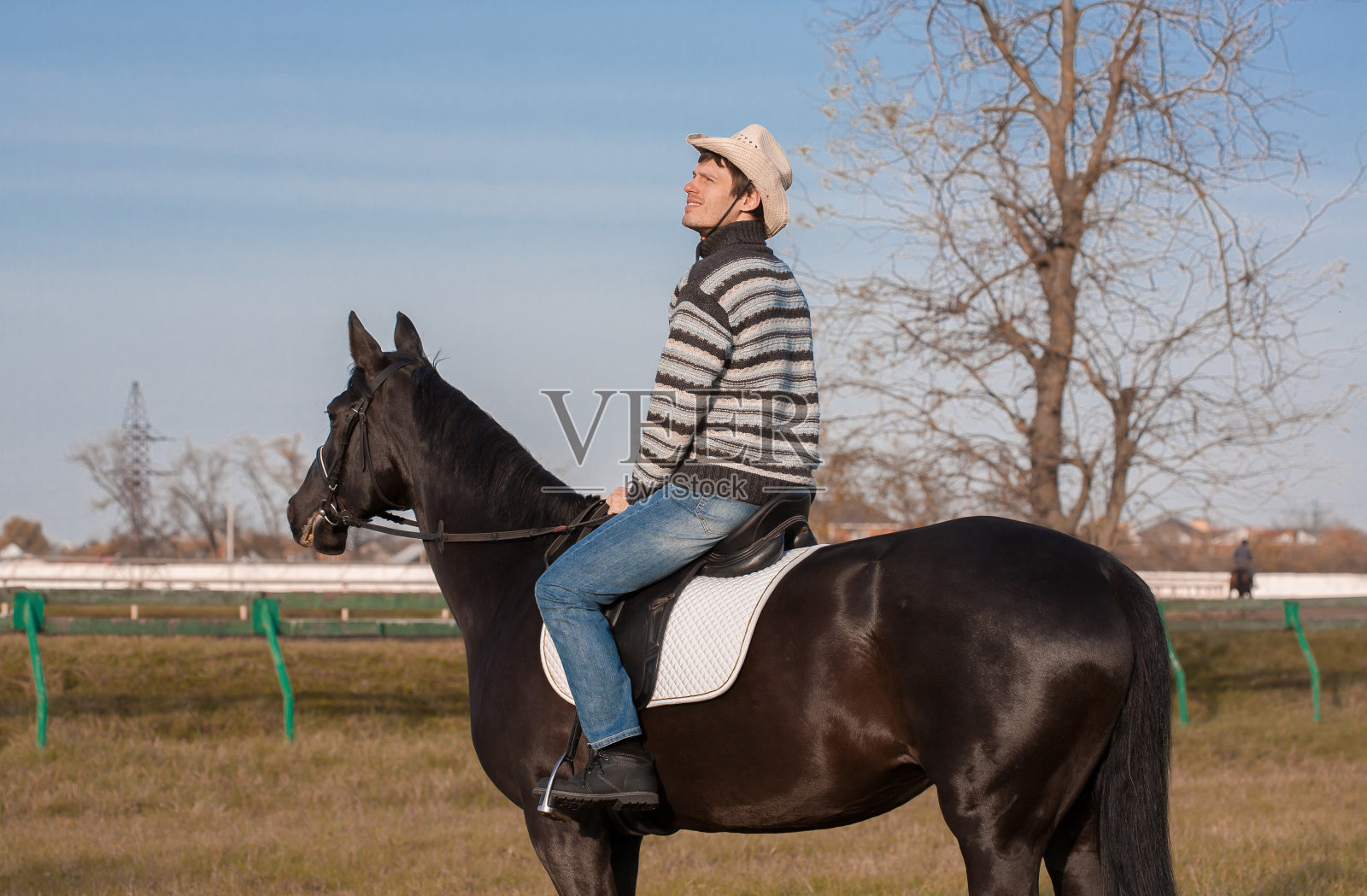 骑马的男人，条纹套衫，蓝色牛仔裤，帽子，特写照片摄影图片