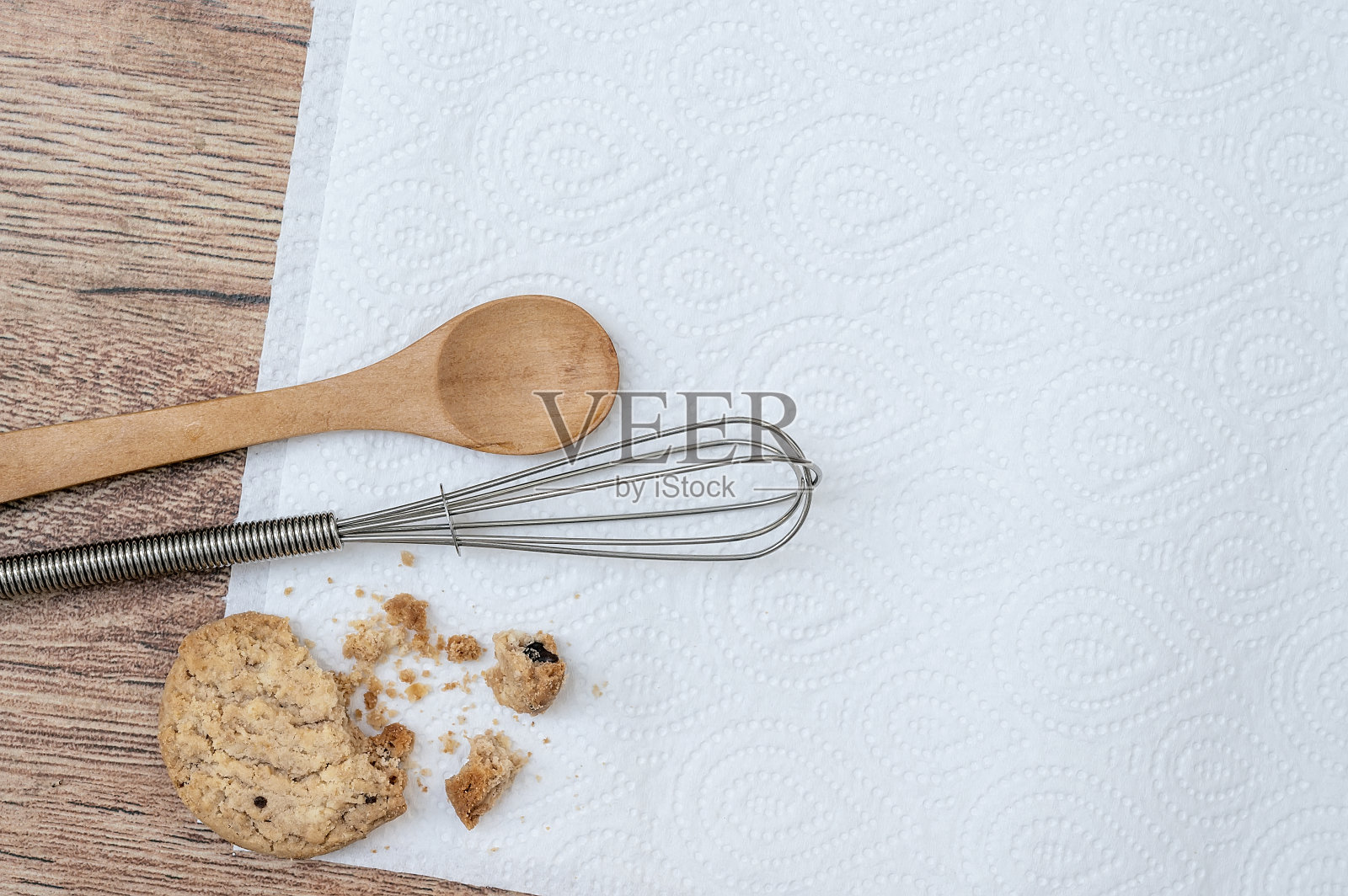俯视图的薄片饼干，木勺和金属蛋打器上的白色厨房毛巾在木桌上照片摄影图片