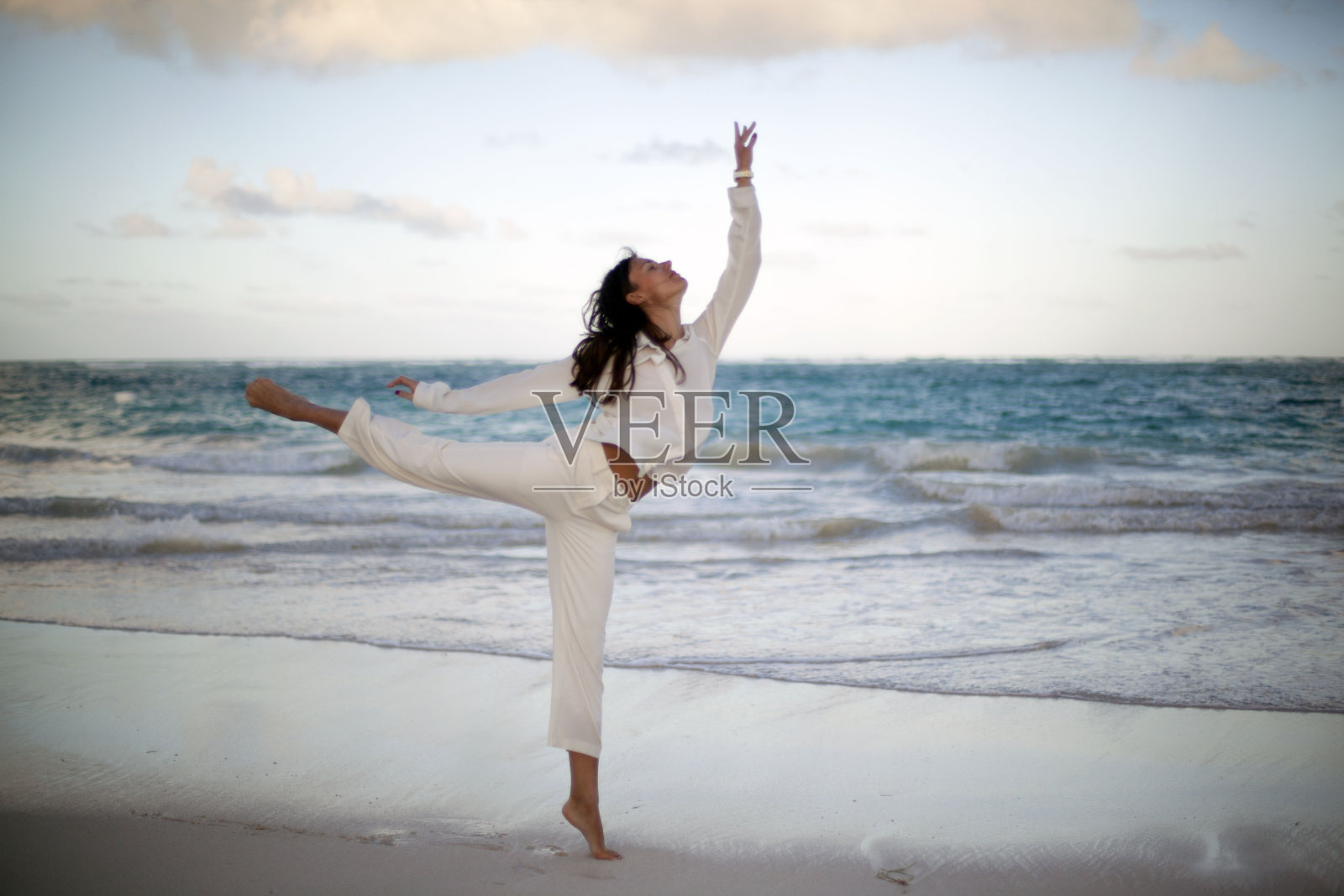 年轻美丽的女人穿着白色衣服在热带海滩上跳舞日落照片摄影图片