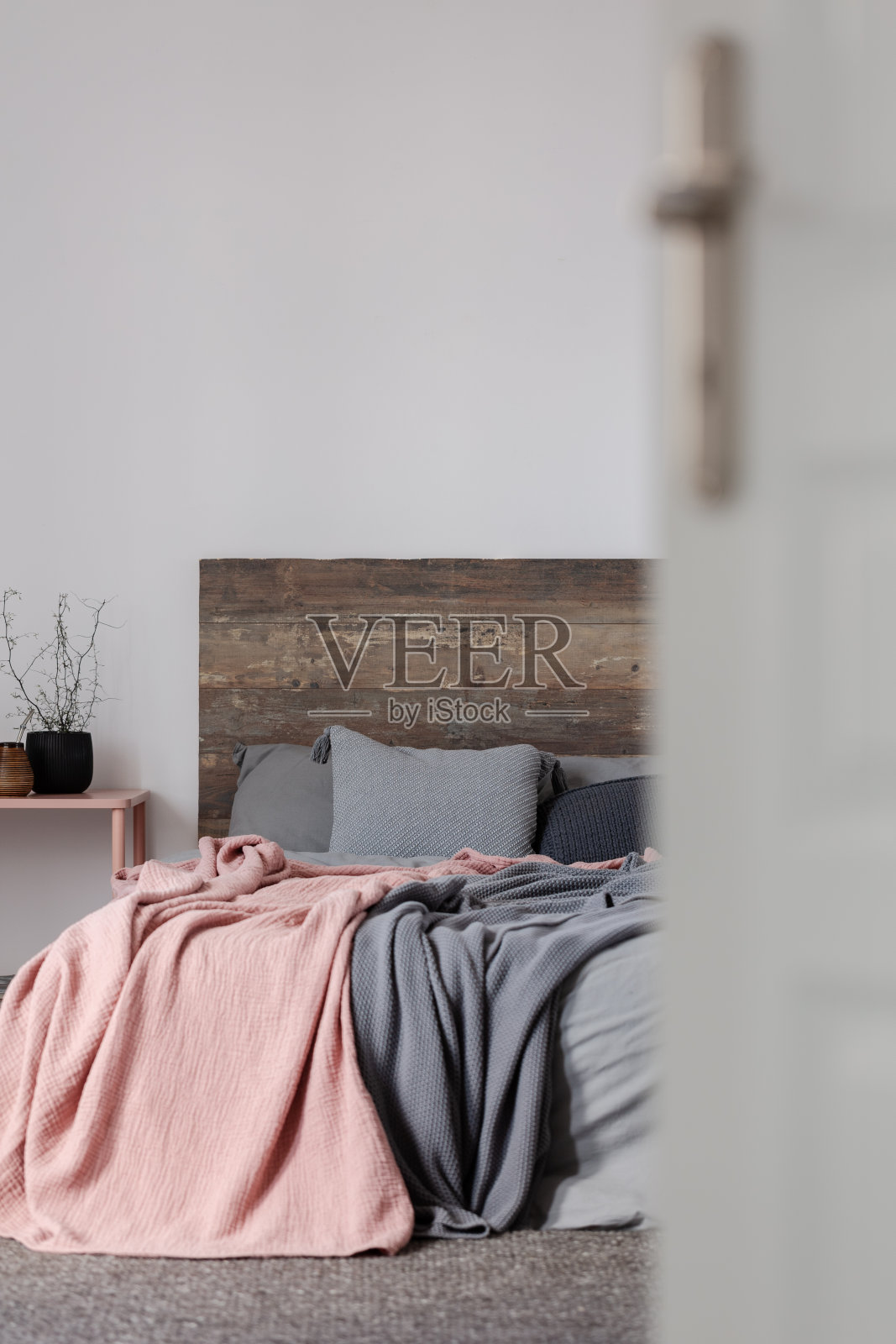 淡粉色和灰色毯子上的灰色床上木质床头板的特大号床照片摄影图片