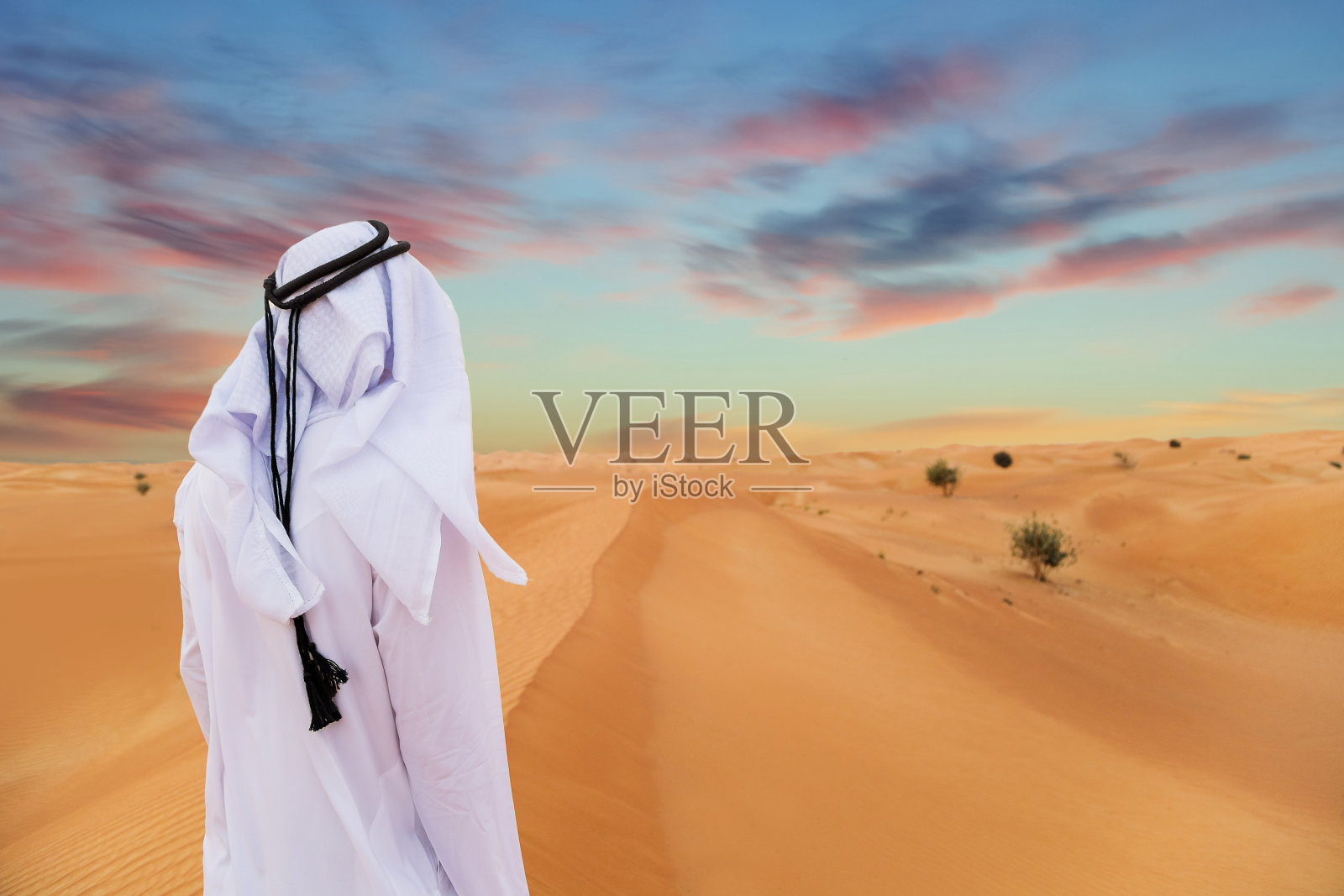 沙漠中穿着阿联酋传统服装的阿拉伯人。照片摄影图片