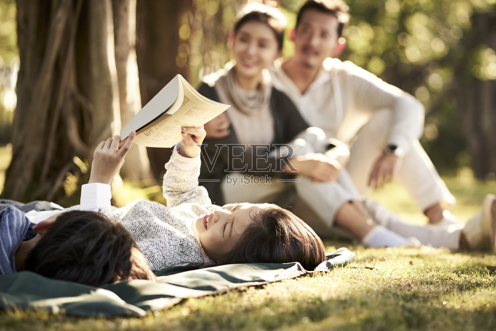 两个亚洲孩子躺在草地上看书照片摄影图片