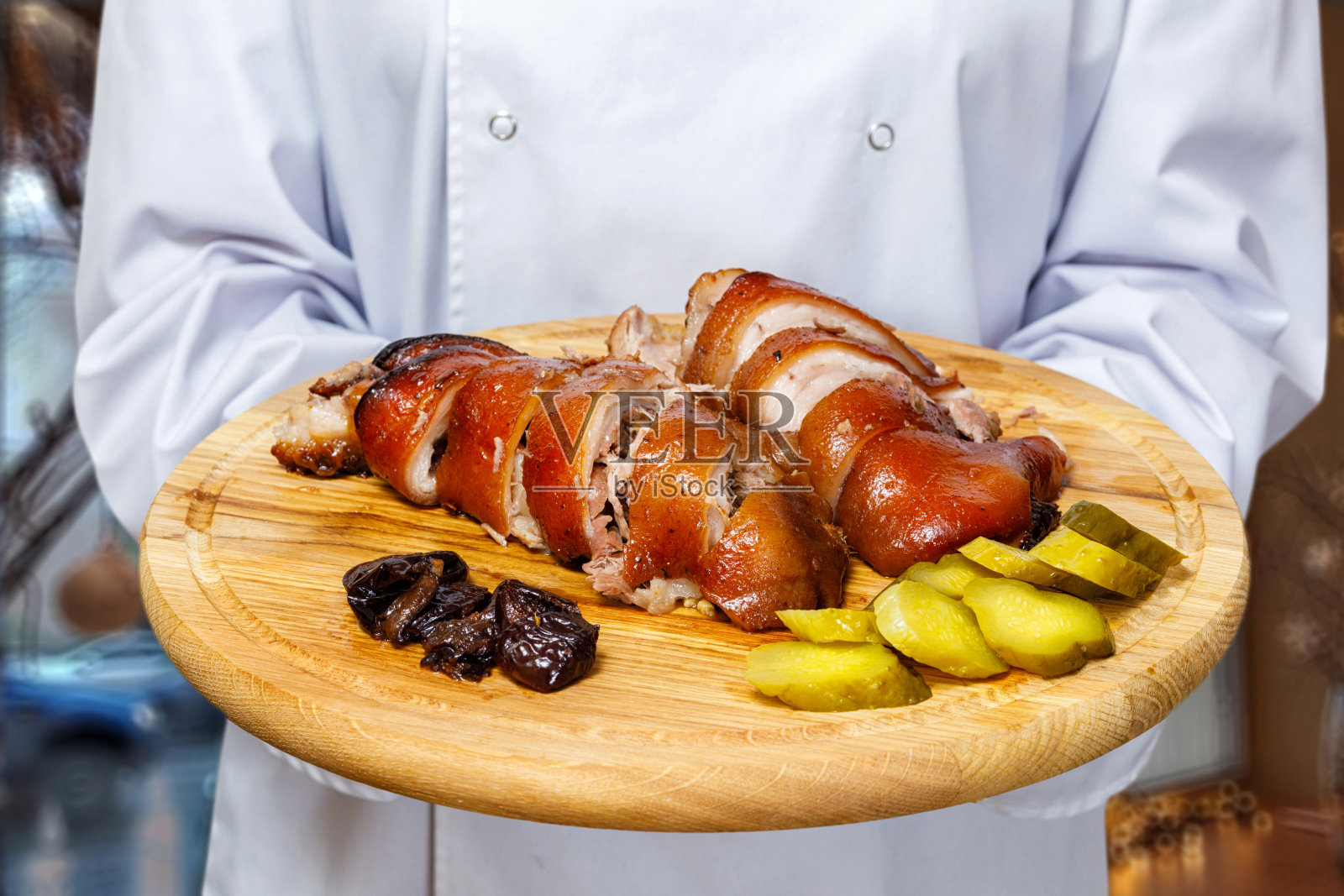 一个厨师端着一个盘子，上面放着烤猪肉和蔬菜。照片摄影图片