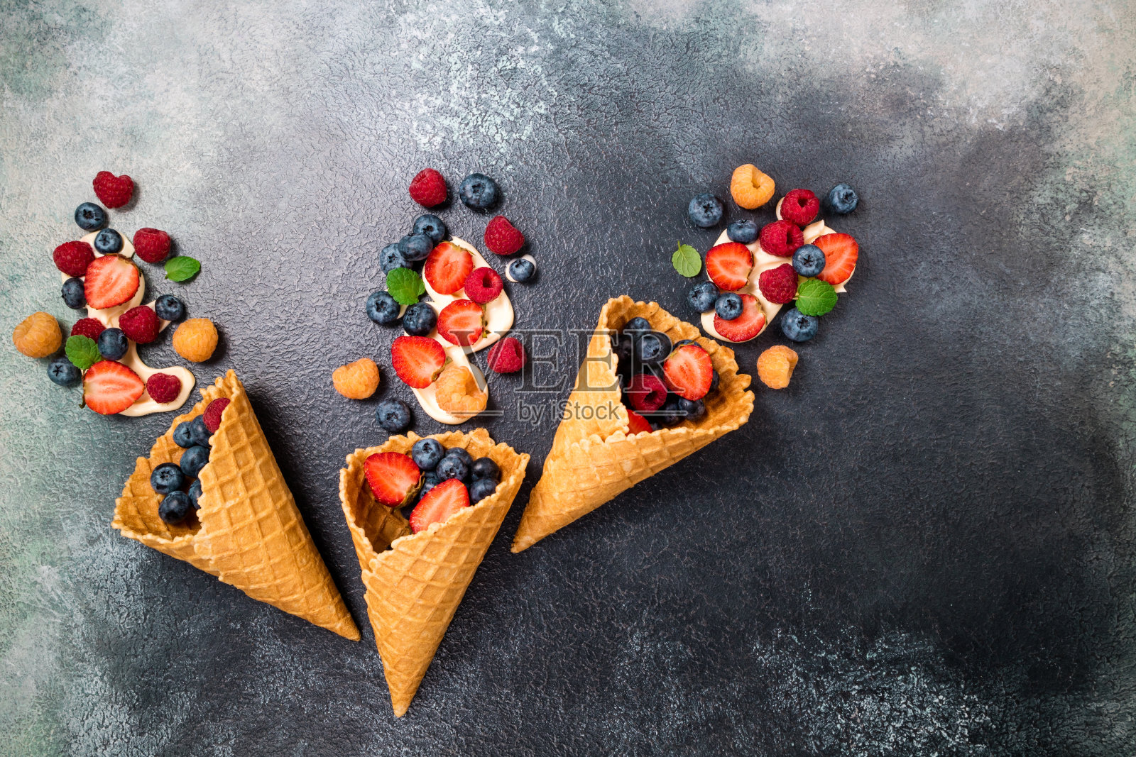 新鲜浆果和冰淇淋蛋卷里的奶油。甜点是草莓、覆盆子、蓝莓。健康饮食、节食食品和营养的概念。夏天的背景照片摄影图片