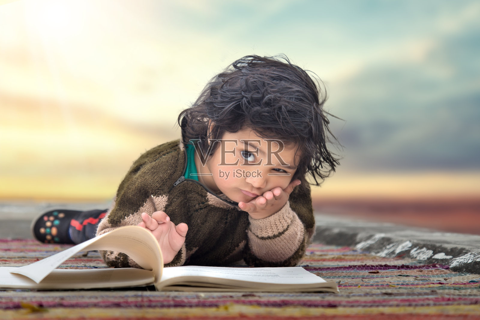 小女孩早早地学习看书，躺在地板上的毯子上。教育激励的概念。照片摄影图片