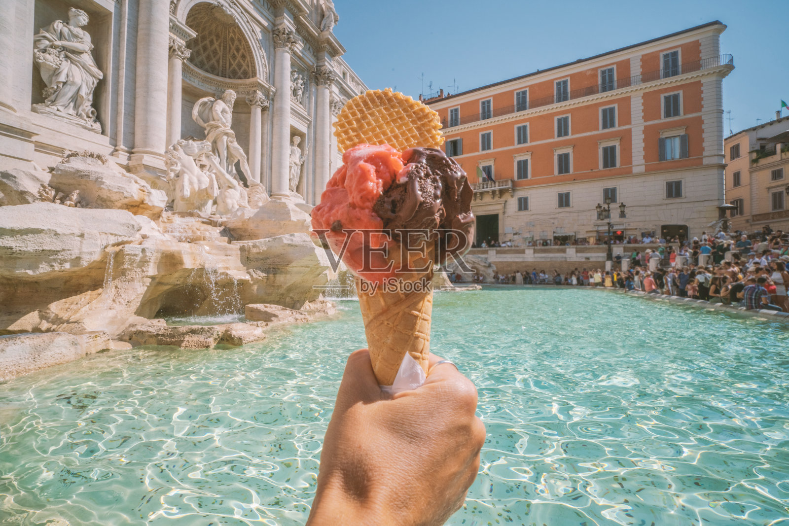 意大利罗马的特莱维喷泉上，一只手拿着意大利冰淇淋照片摄影图片