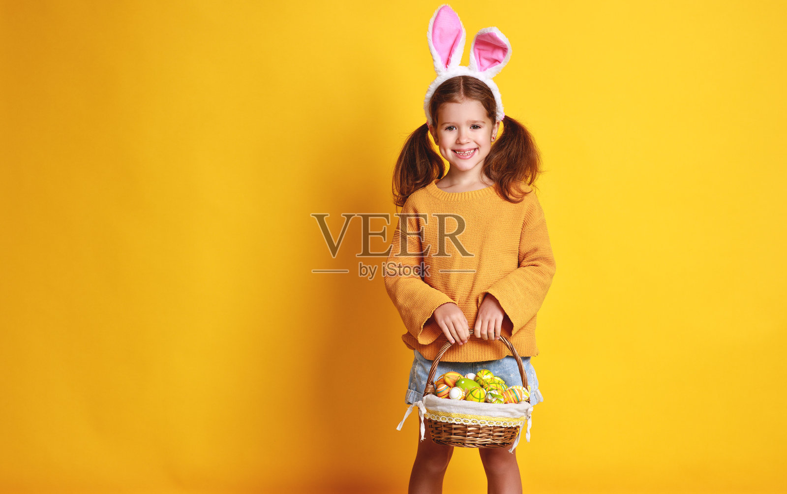 有趣快乐的小女孩用黄色的复活节彩蛋照片摄影图片