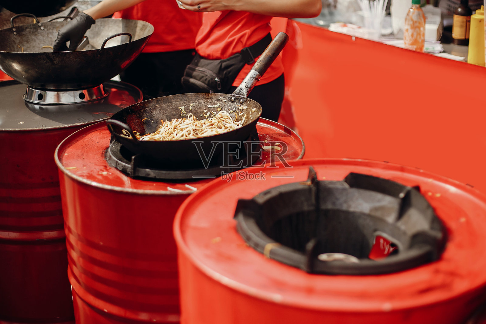 亚洲街头美食节。厨师在火上用平底锅煮面条和蔬菜。用明火在锅里炒日式蔬菜和虾面照片摄影图片