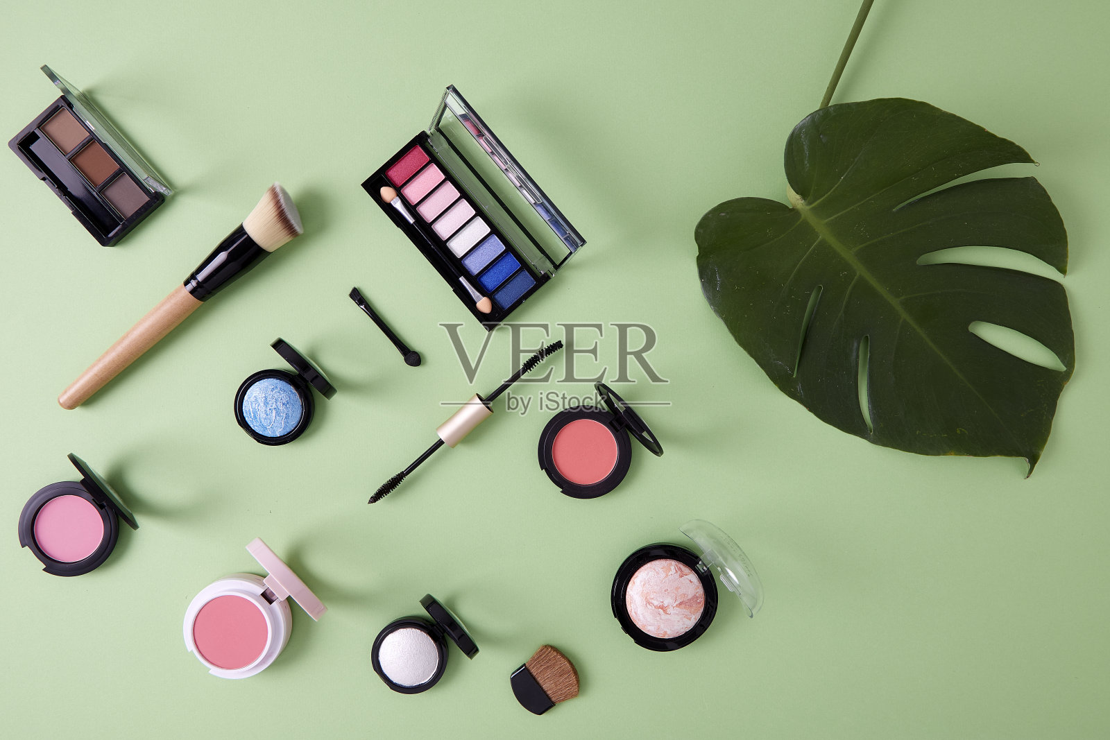 平铺彩妆用粉彩纸将美容产品排列在绿色背景上，有机彩妆的概念照片摄影图片