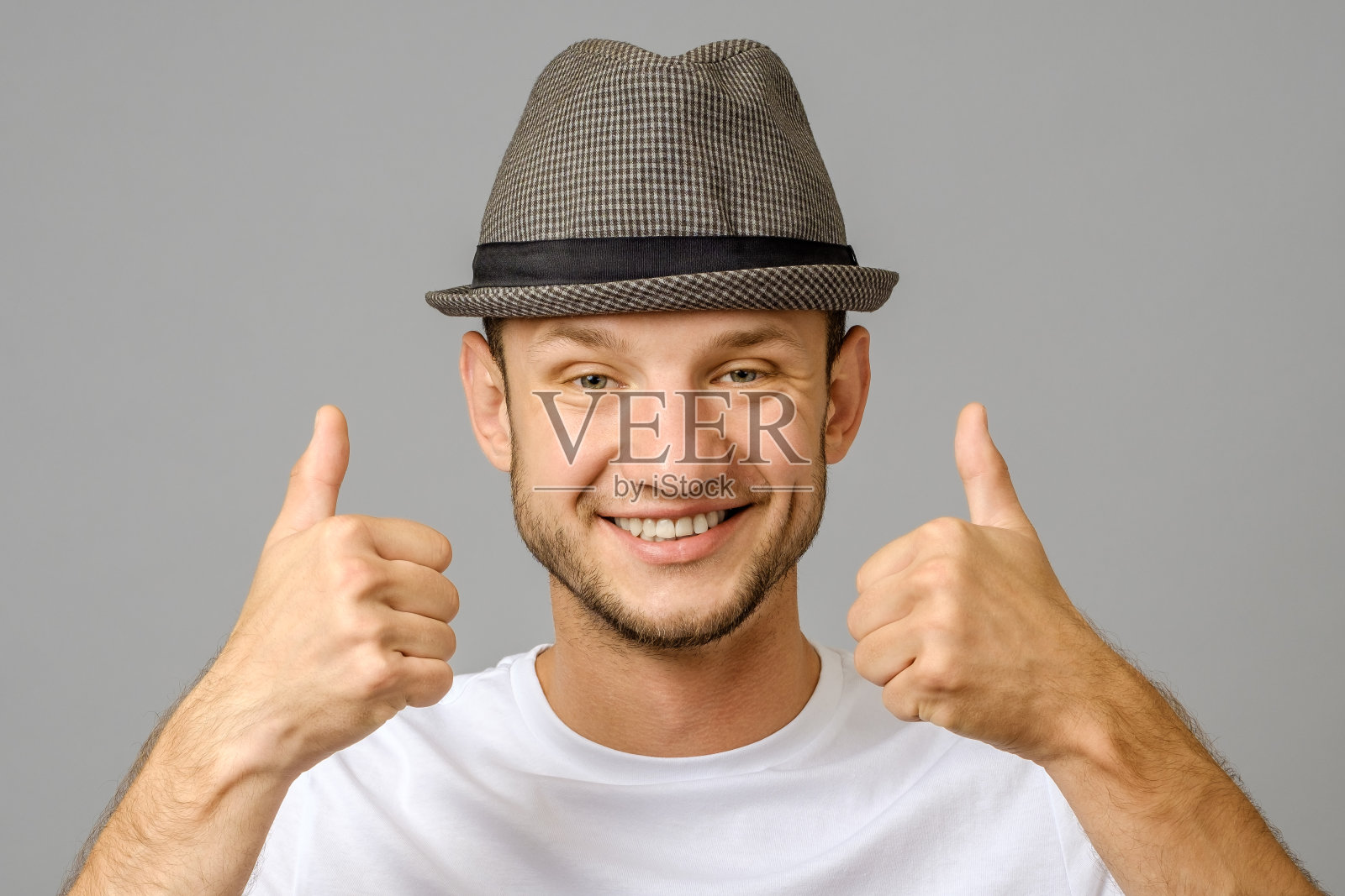 灰色背景上的男子微笑着竖起两个大拇指的肖像照片摄影图片