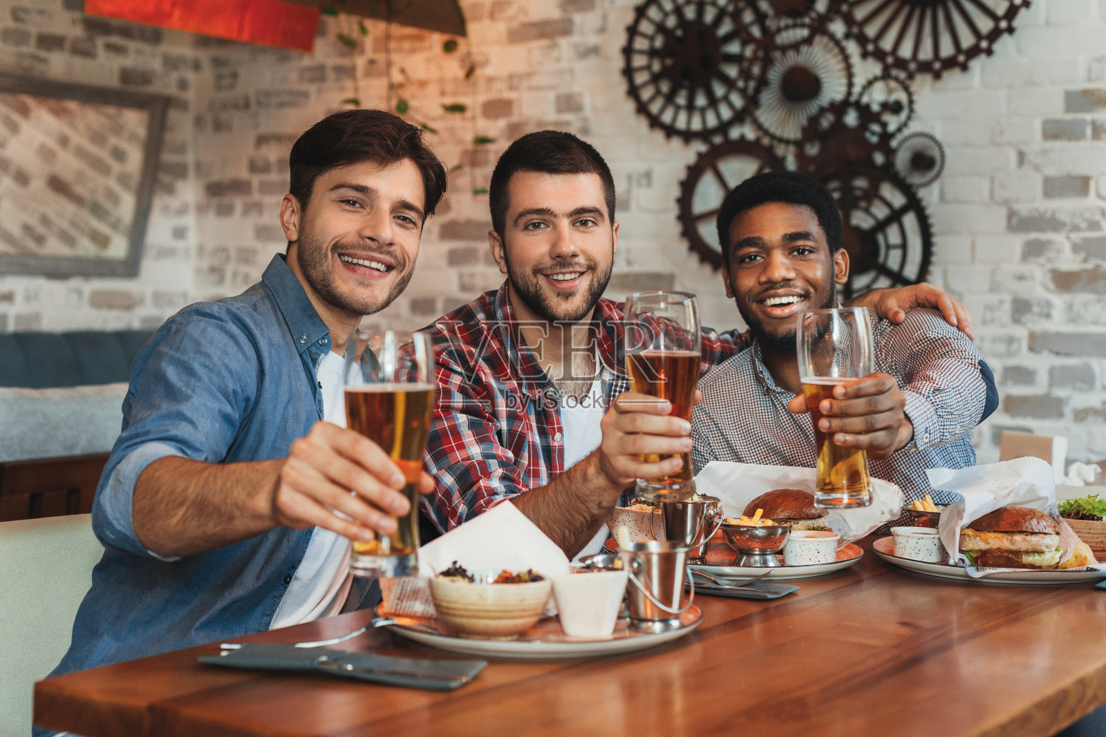 和朋友一起喝啤酒。男人们一起坐在酒吧里照片摄影图片