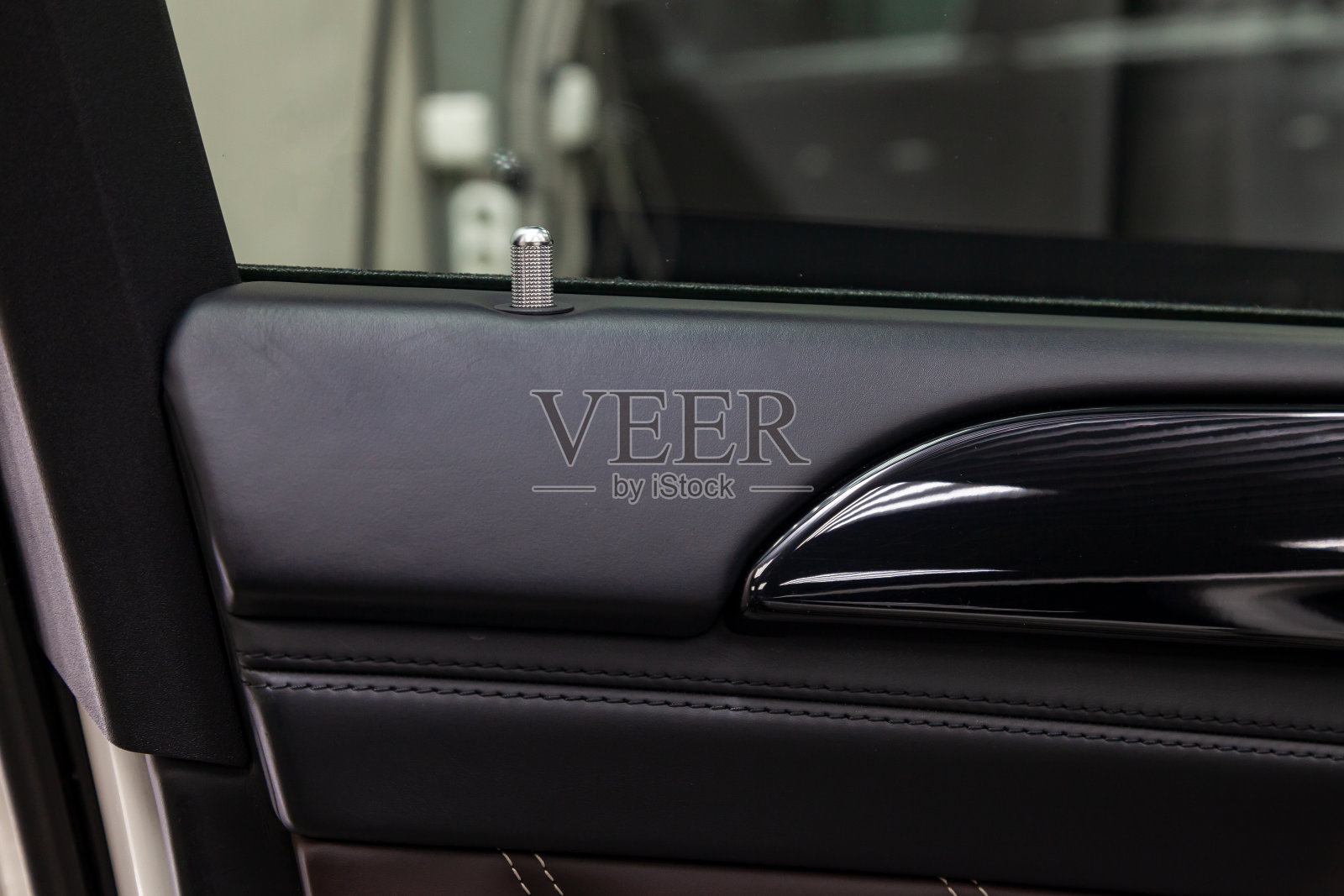 一个现代豪华汽车内部的一个近距离的视图，以锁销的一个银色门由铬与黑色木材装饰元素照片摄影图片