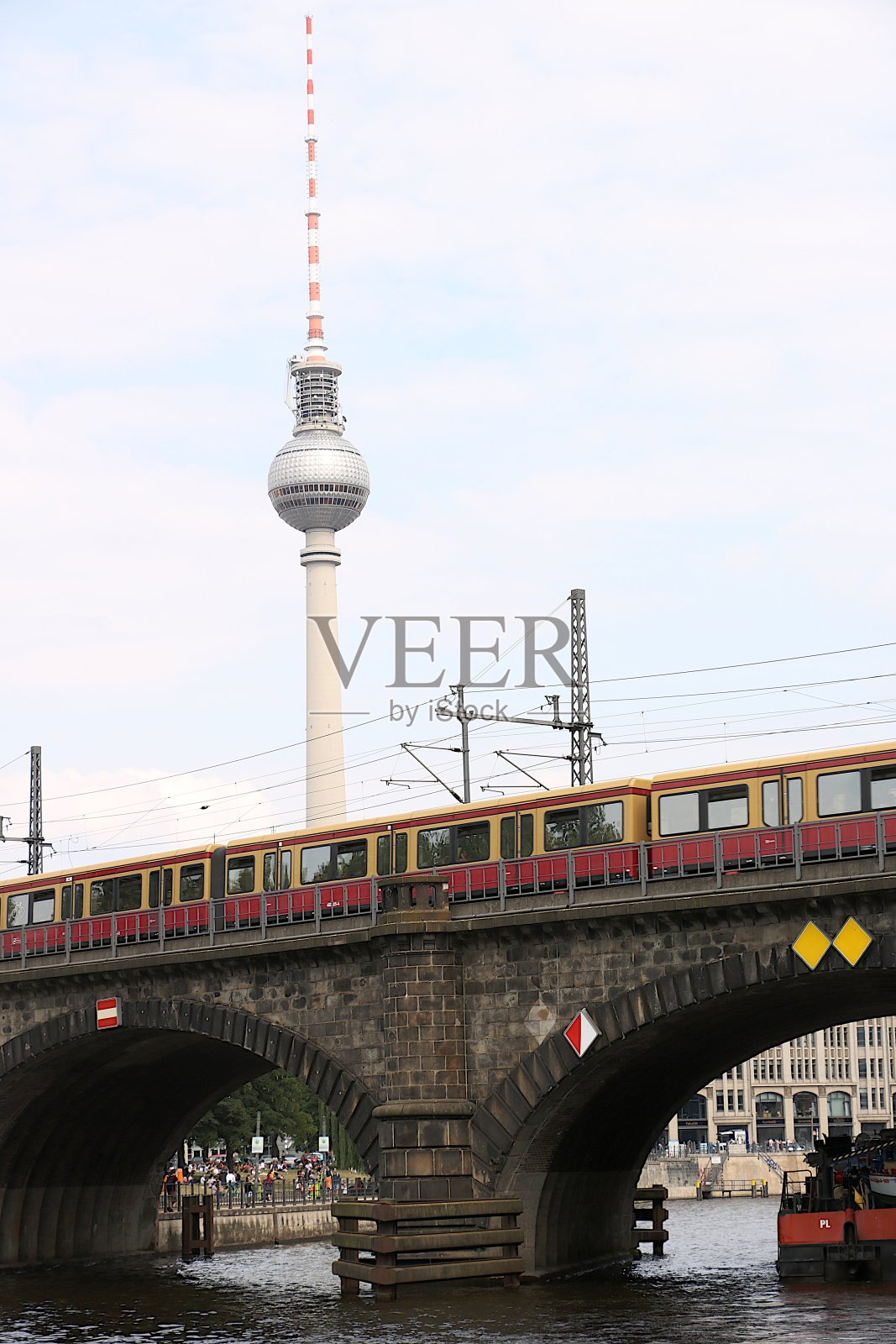 火车驶过河上的石桥。在背景中你可以看到电视塔。照片摄影图片