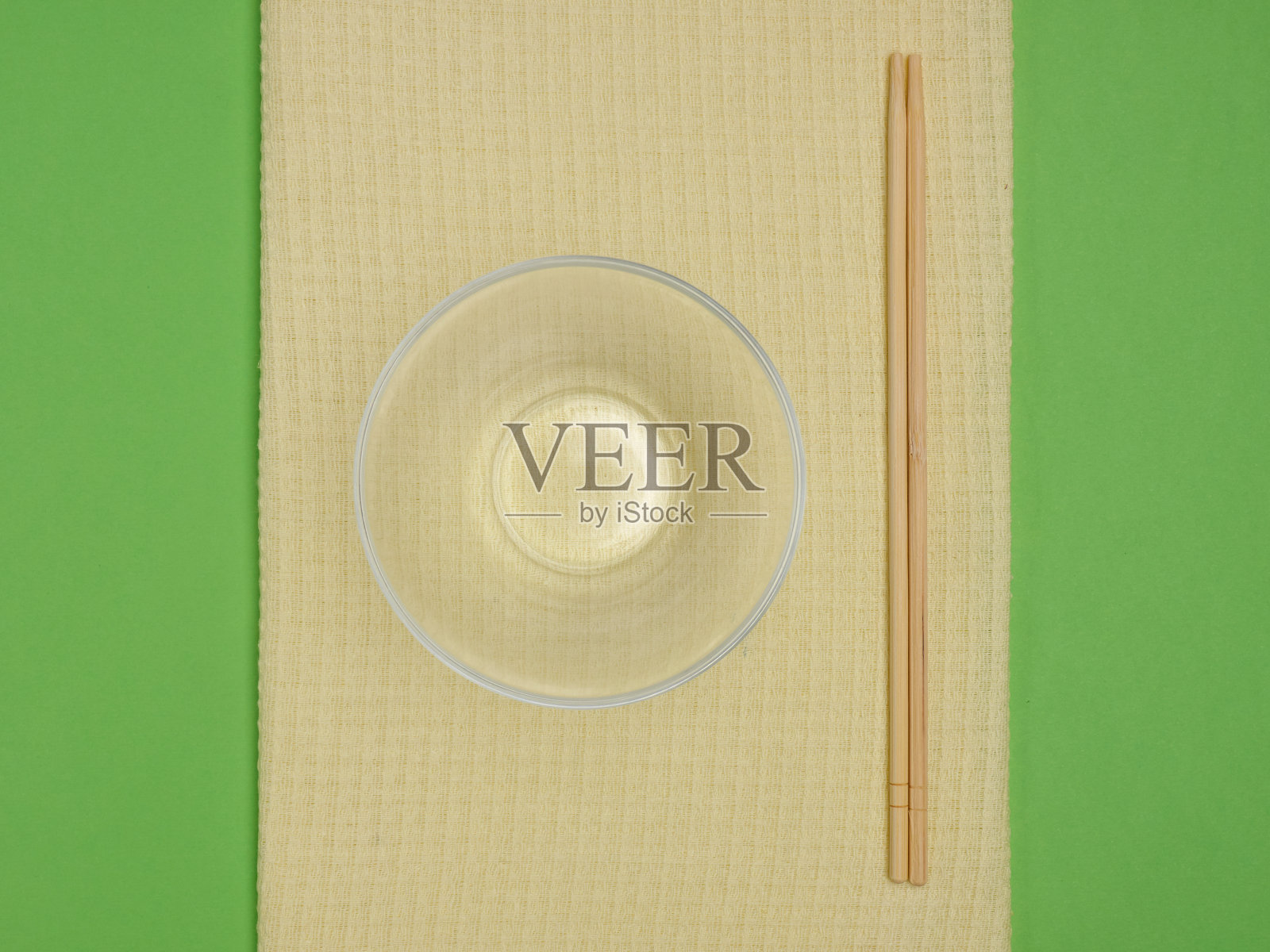 玻璃碗，亚洲筷子，铜叉子和勺子，黄色毛巾，绿色背景的copyspace照片摄影图片