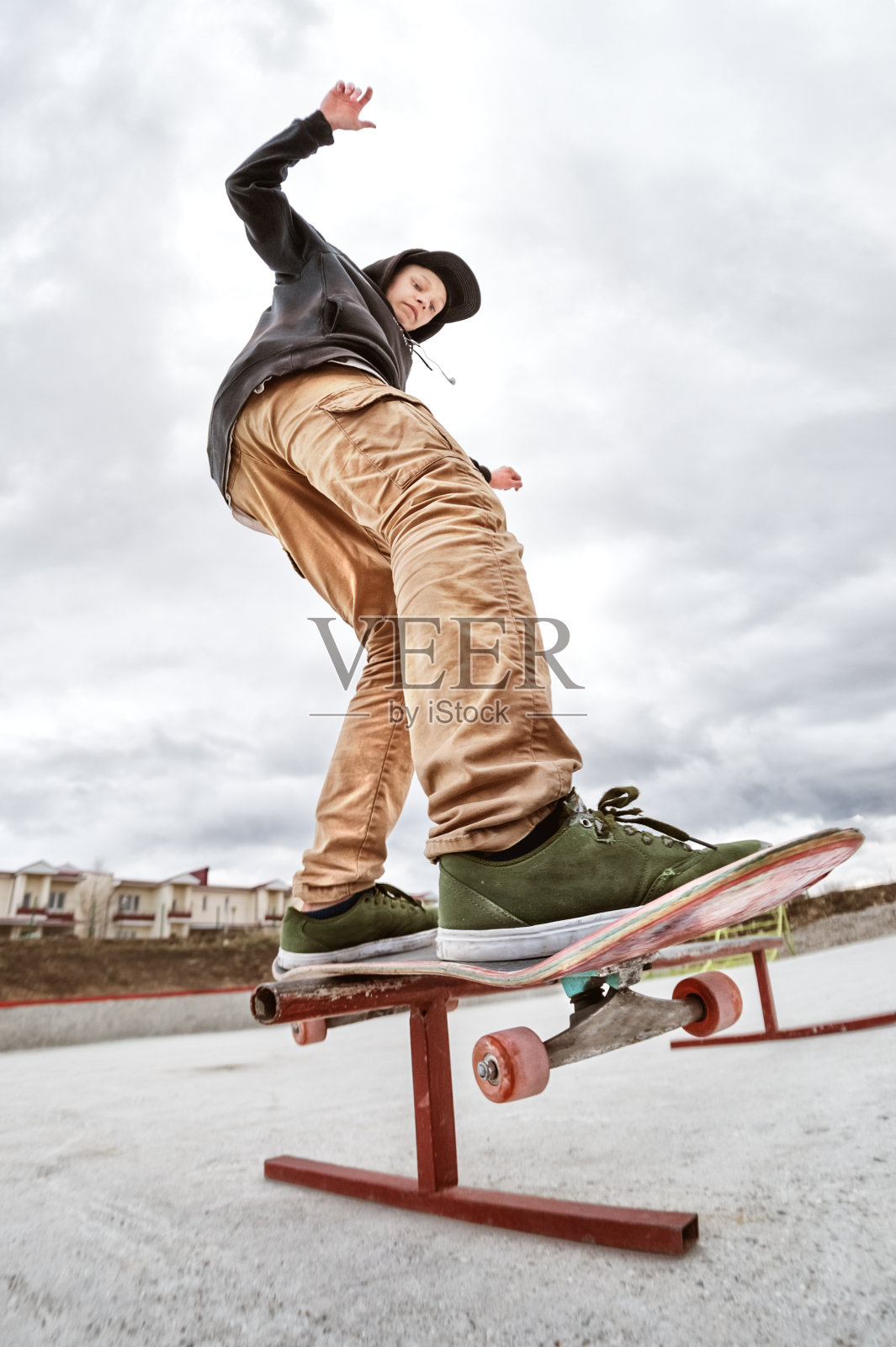 十几岁的溜冰者在一个滑板公园里，穿着连帽运动衫和牛仔裤滑过滑板的栏杆照片摄影图片