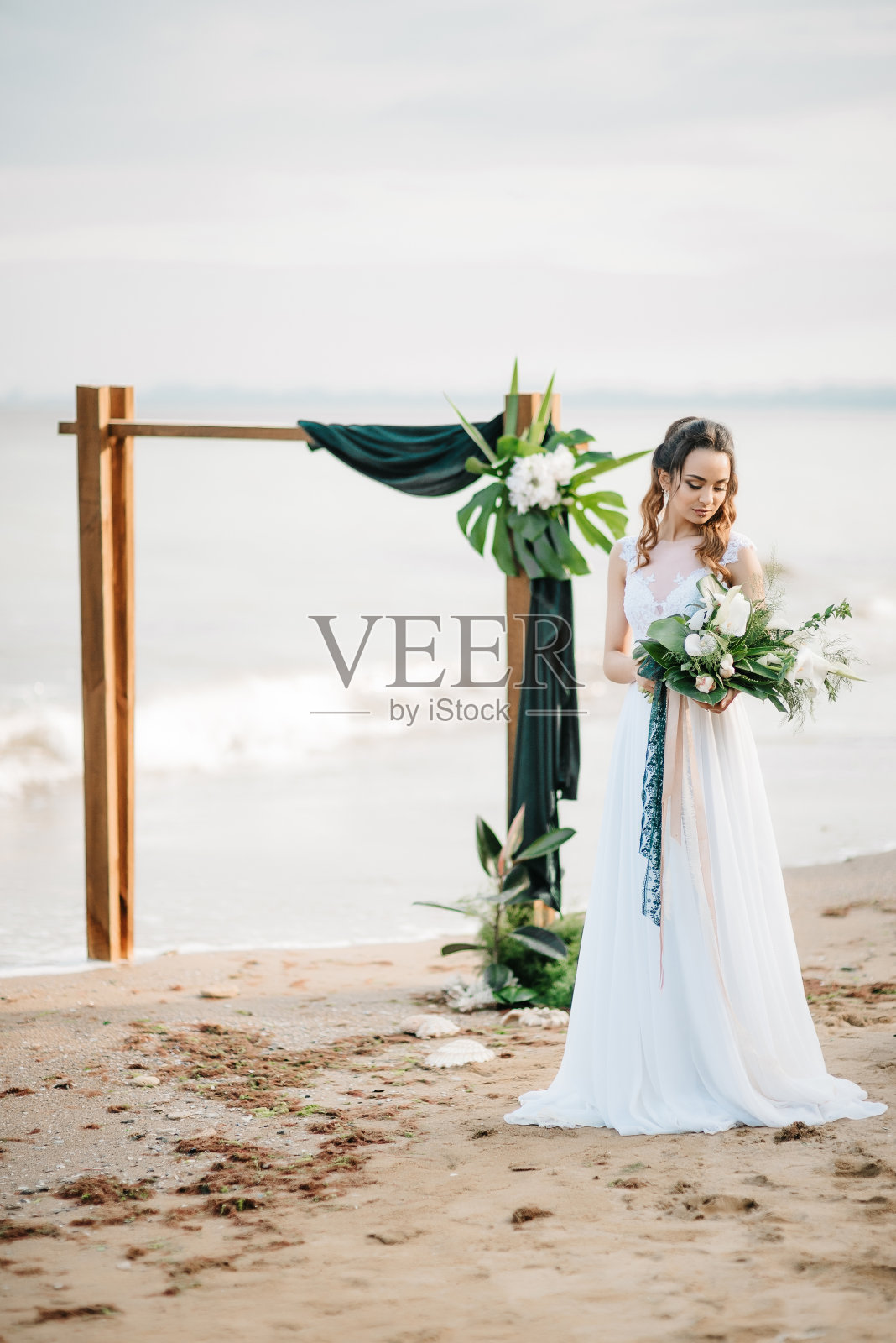 在海边，新娘手拿婚礼花束照片摄影图片