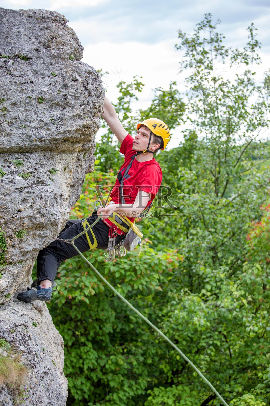 照片的运动员在头盔爬过岩石的背景绿树照片摄影图片