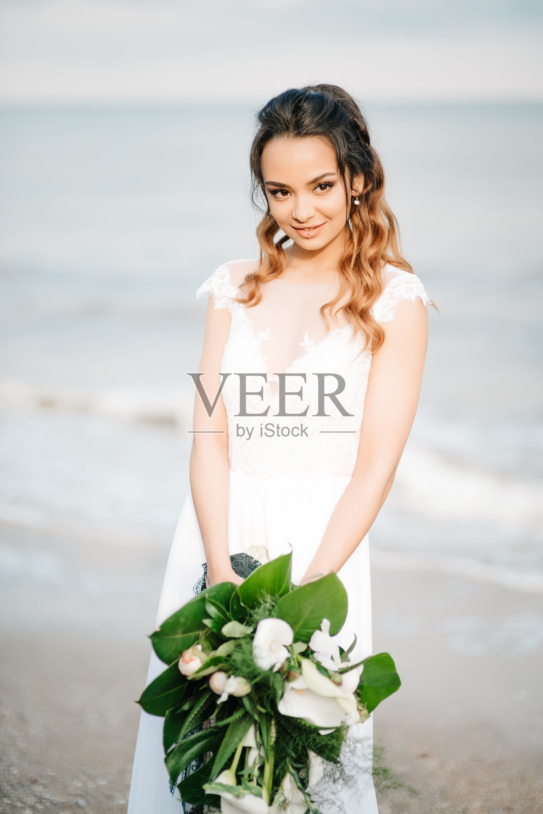 在海边，新娘手拿婚礼花束照片摄影图片