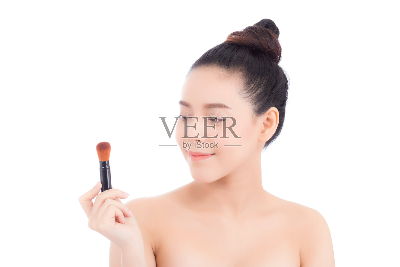 肖像亚洲女性用腮红刷在白色的背景上化妆，美丽的女孩拿着腮红，护肤和化妆的概念。照片摄影图片