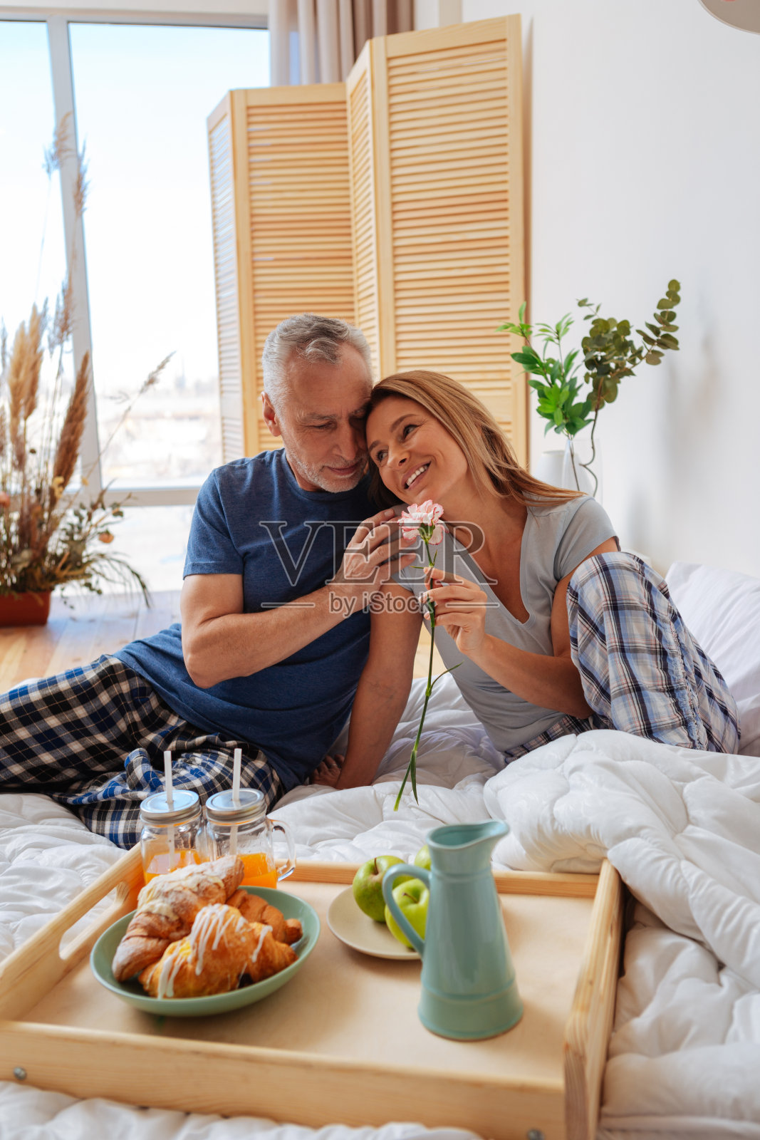 妻子倚着丈夫的肩膀在床上吃早餐照片摄影图片