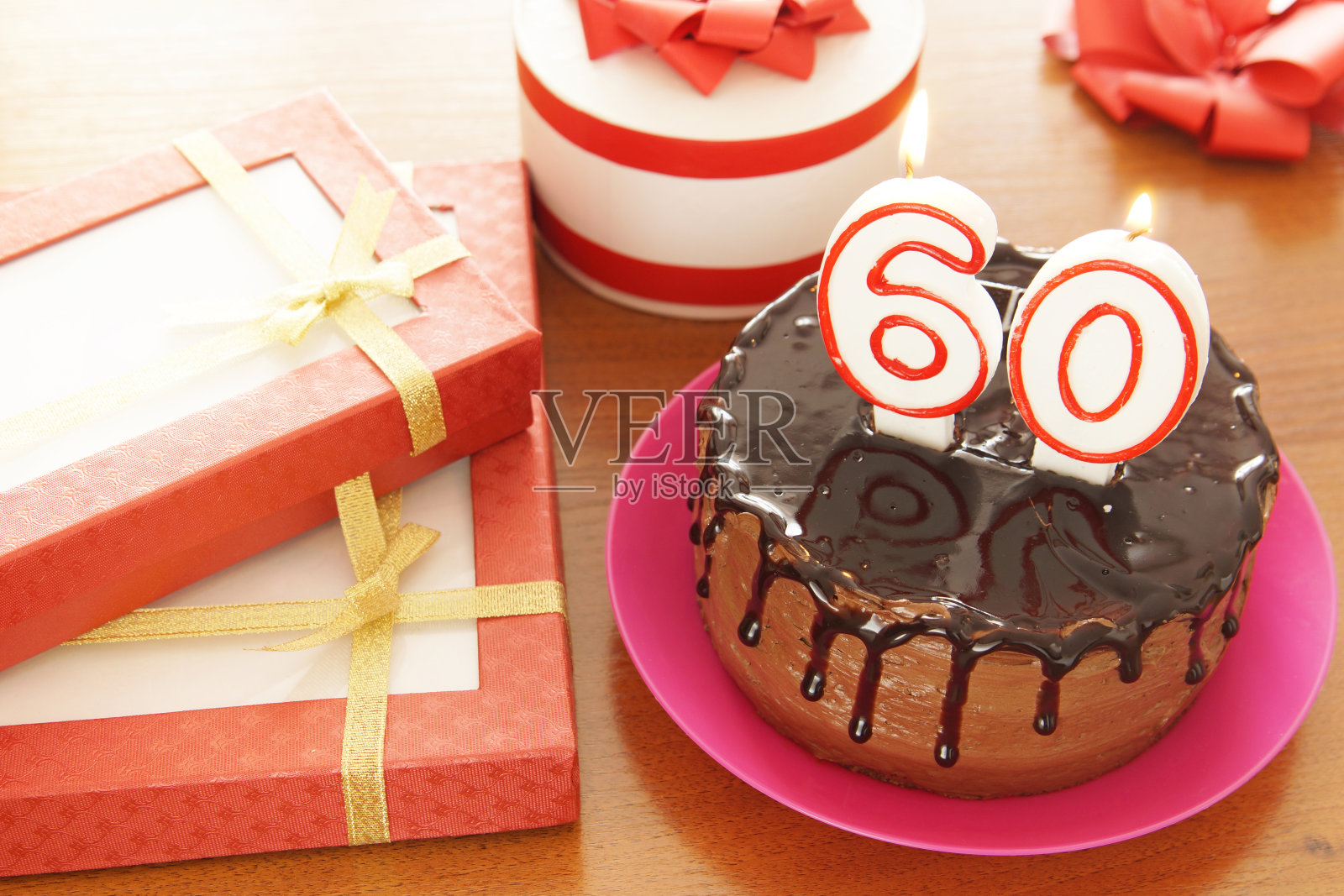 庆祝六十大寿。蛋糕上有点燃的数字蜡烛，桌子上有许多礼物照片摄影图片